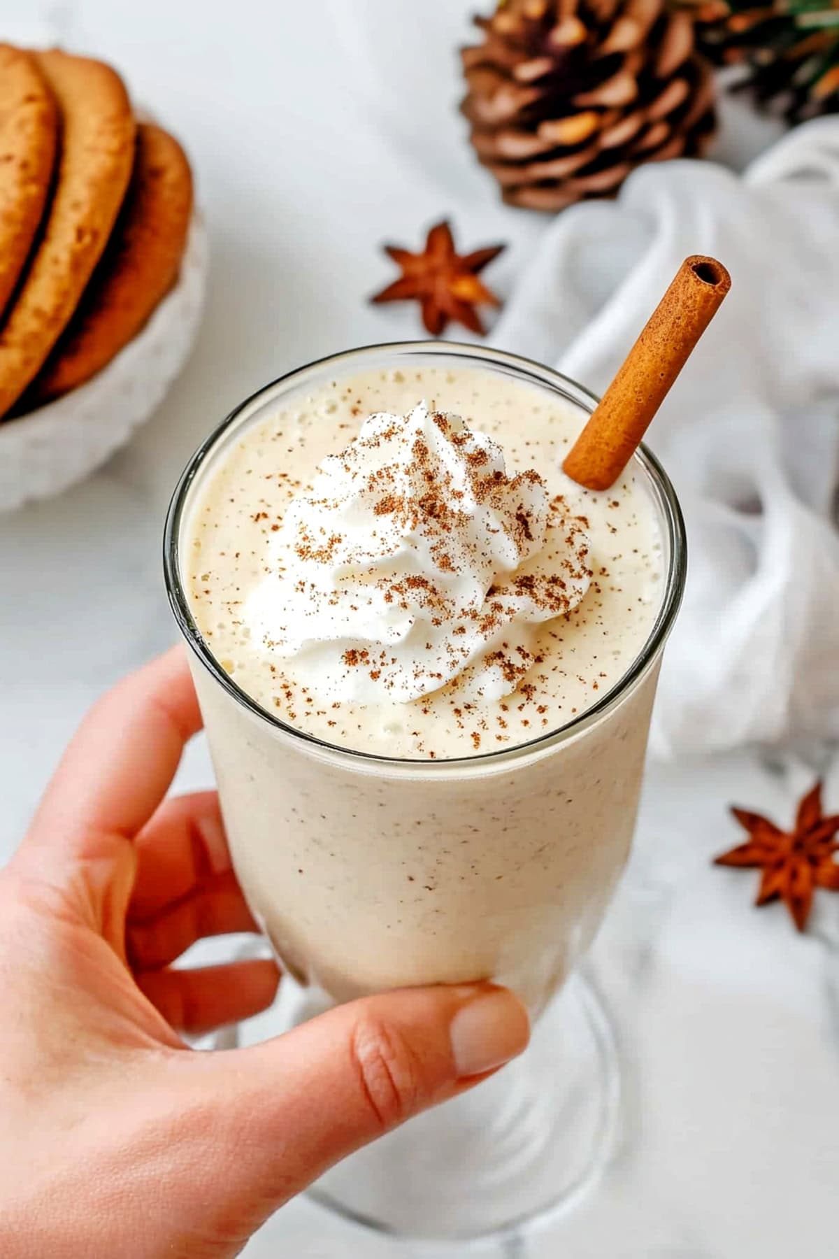 A rich and smooth eggnog milkshake with a swirl of whipped cream, served in a tall glass.