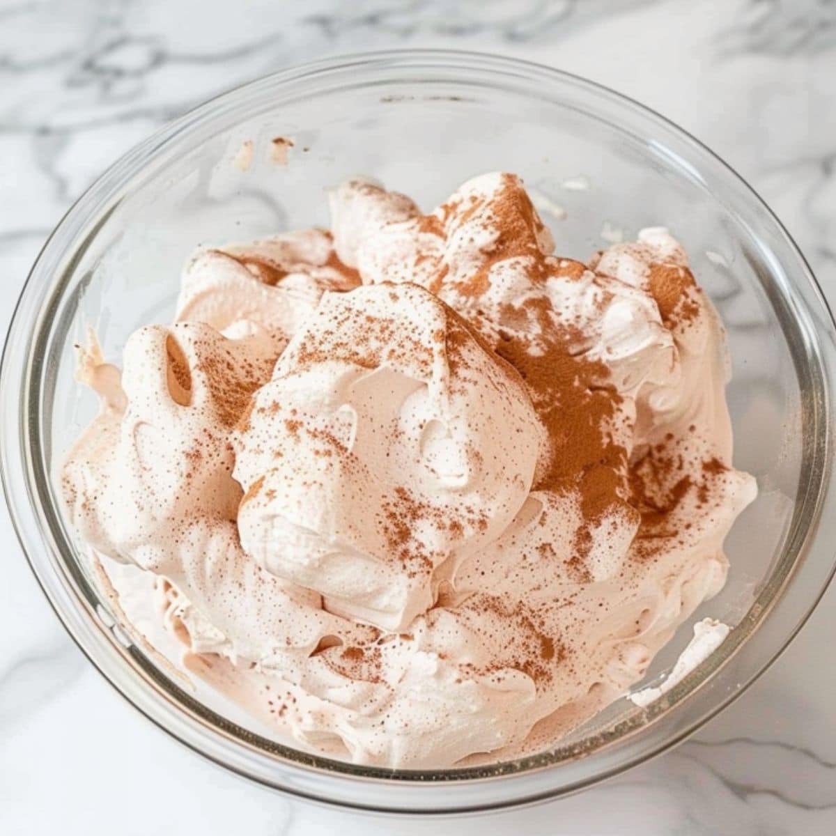 Whipped cream with hot chocolate mix whipped in a glass mixing bowl.