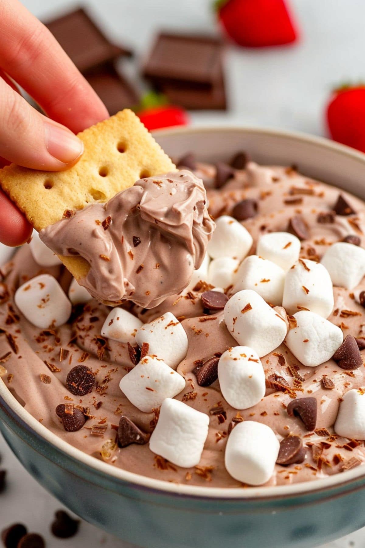 Biscuit dipped to a bowl with hot chocolate dip with marshmallows and chocolate chips. 