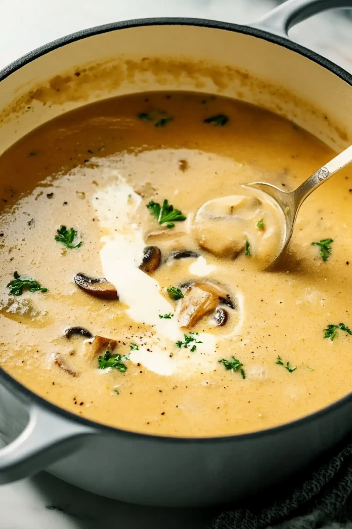 A pot of creamy mushroom soup with sour cream and parsley.