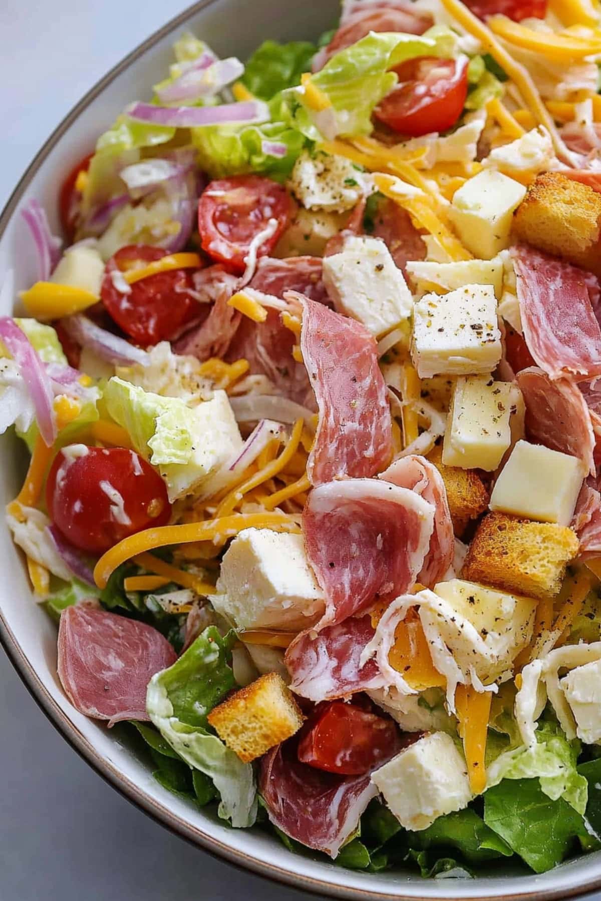 A close-up of Italian grinder salad with cheese, meat, red onions and tomatoes.