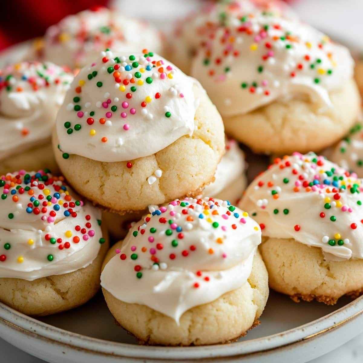 A plate of soft, pillowy Italian ricotta cookies topped with a light glaze and colorful sprinkles