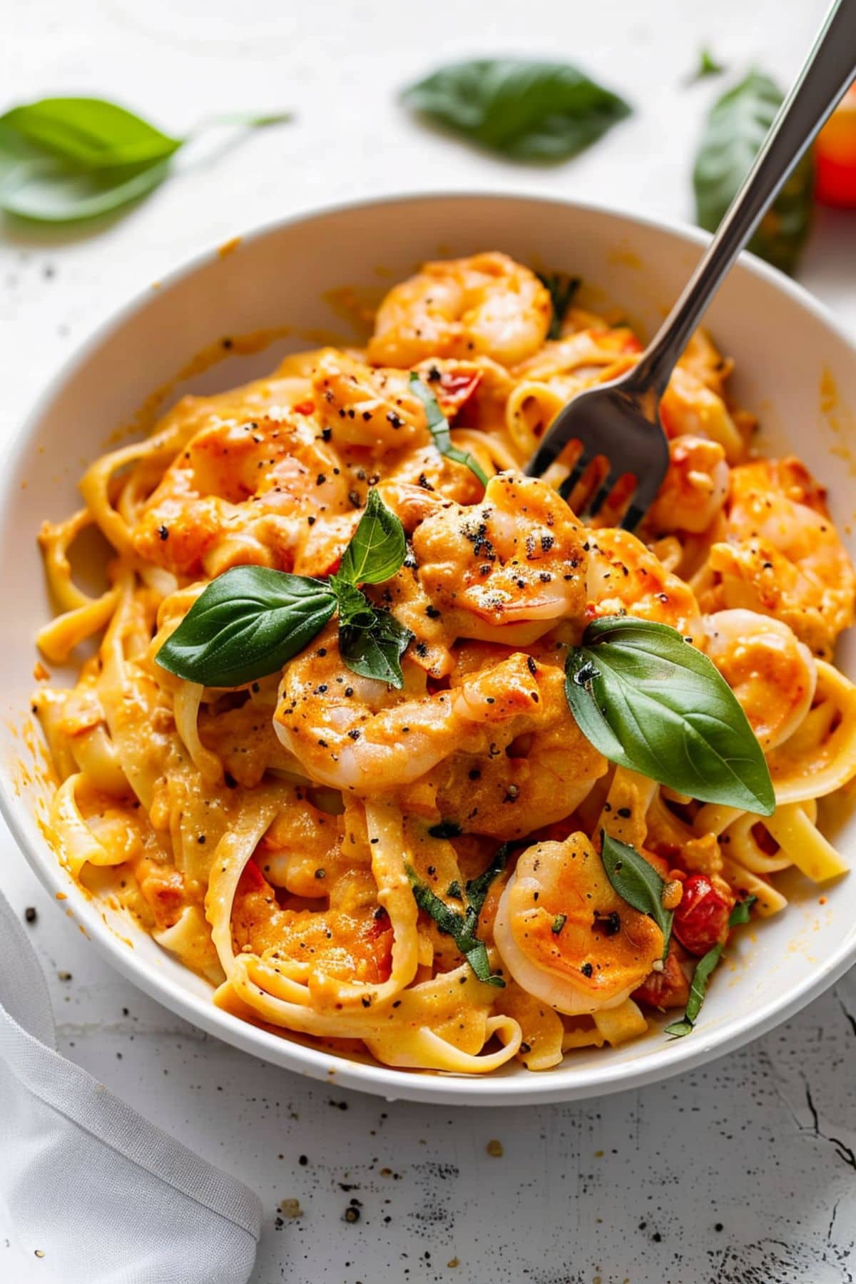 Linguine pasta cooked with shrimp in tossed in creamy tomato sauce  served in a white bowl.