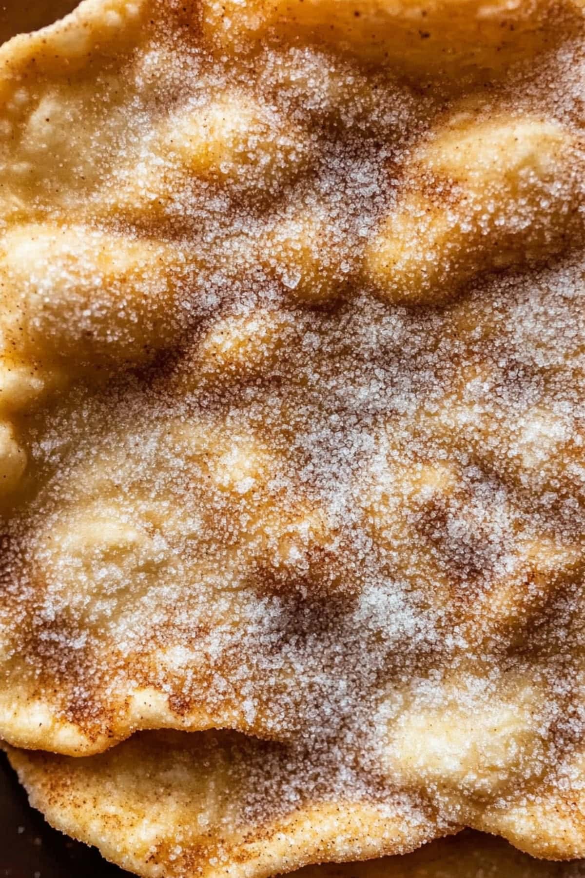 Homemade Mexican bunuelos topped with sugar, close-up.