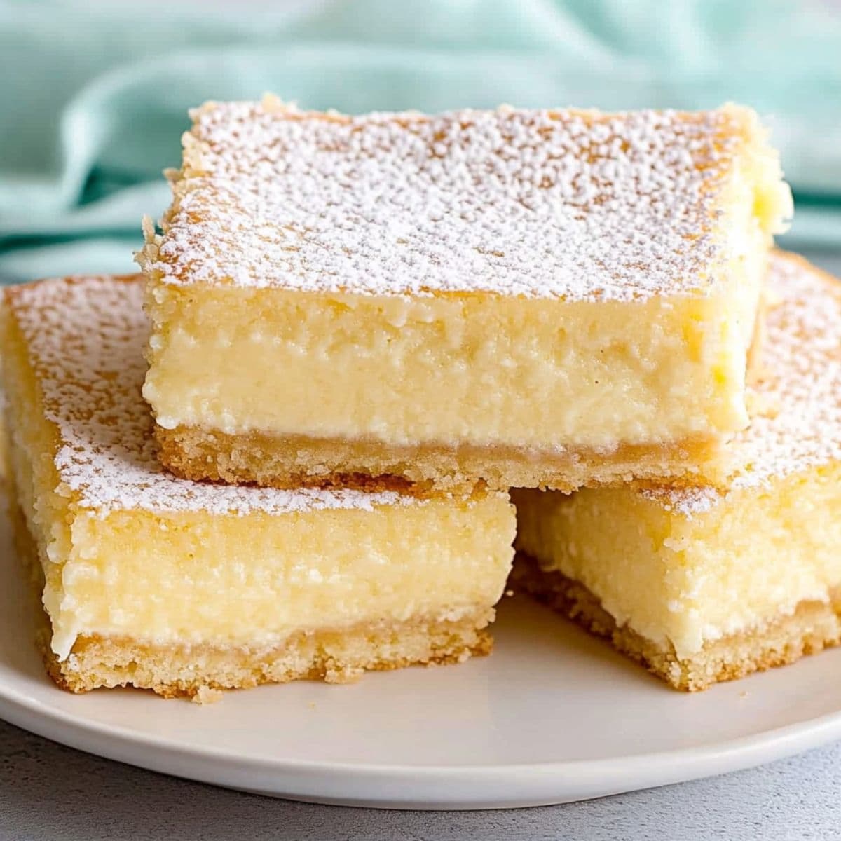 Slice of creamy Neiman Marcus cake, dusted with powdered sugar and served in a white plate.
