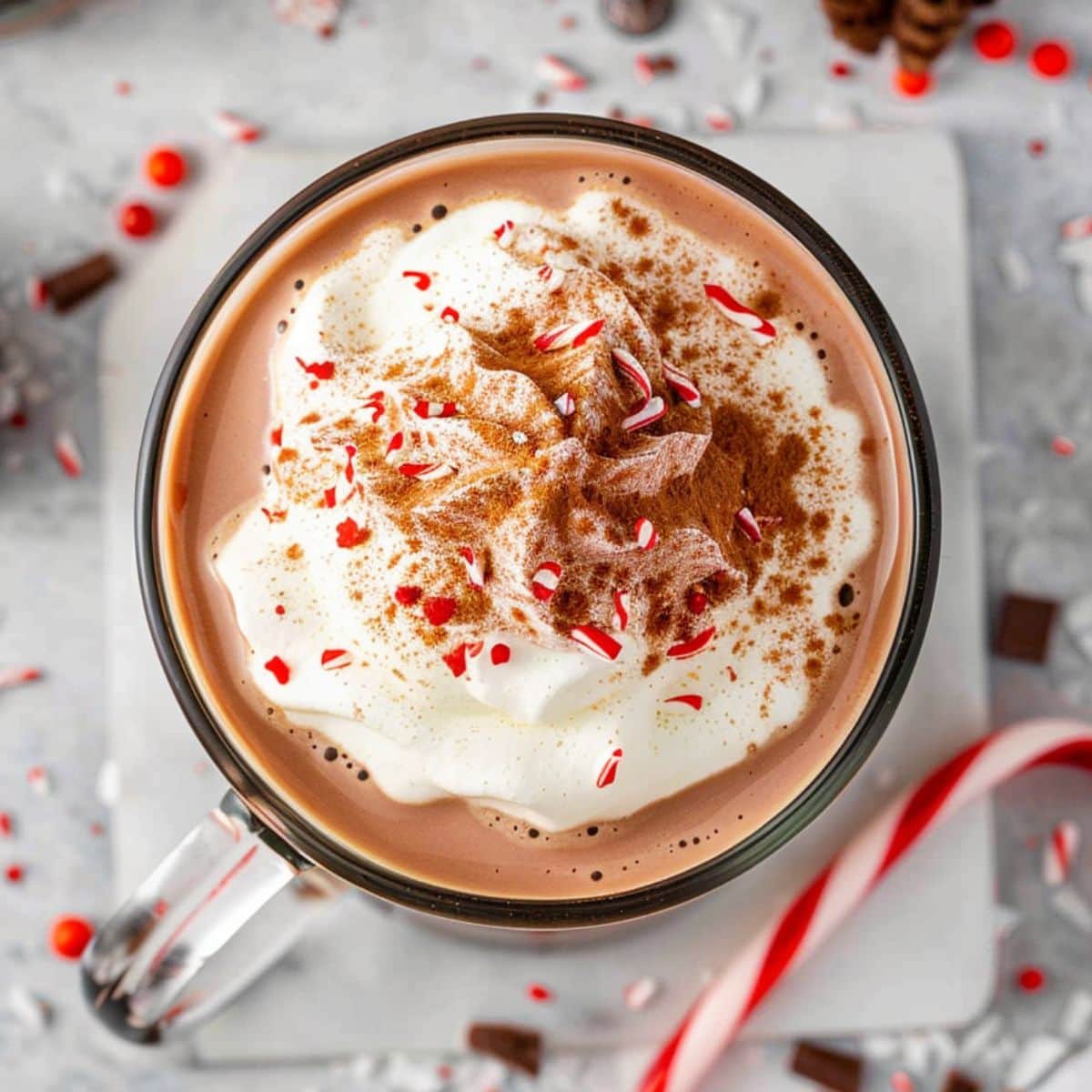 Top view of hot chocolate in a glass  mug topped with whipped cream and crushed peppermint candy.