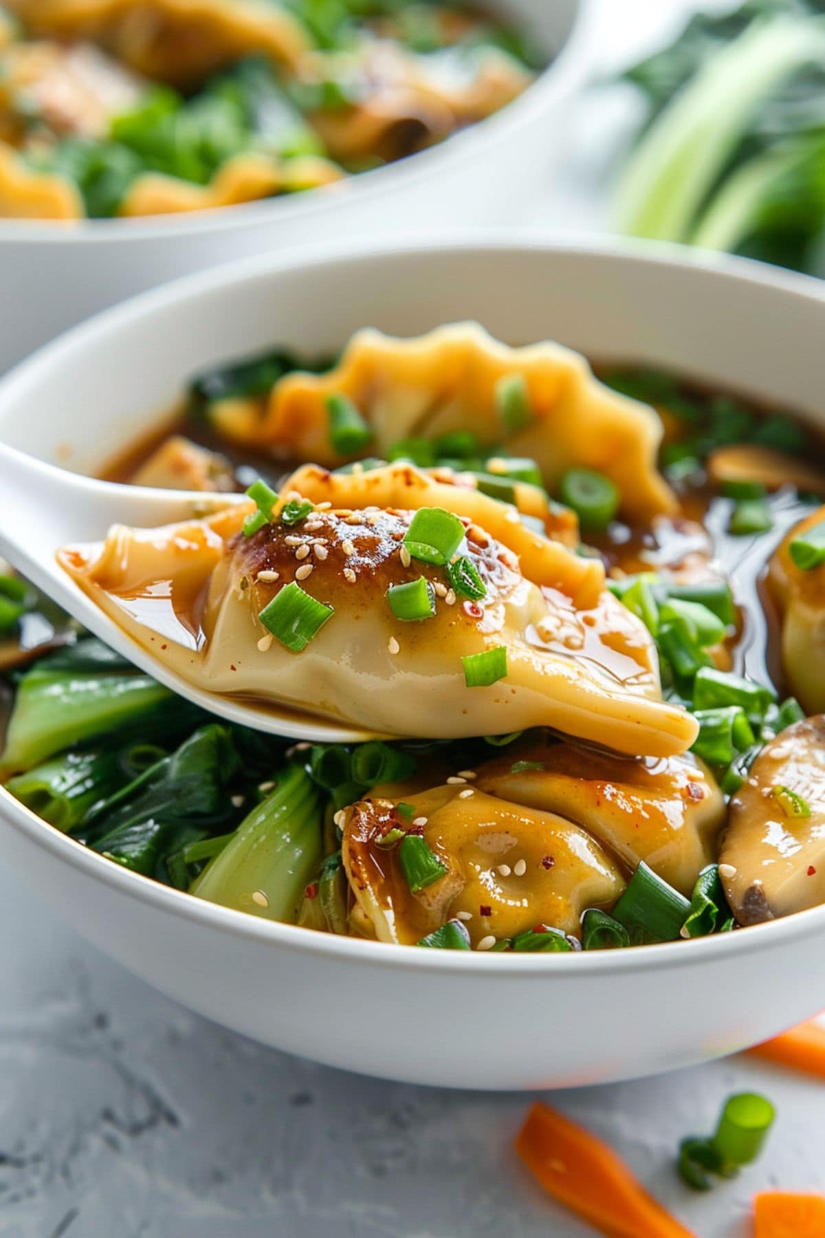 Soup spoon lifting a serving potsticker soup from bowl.