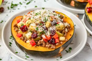 Sausage stuffed acorn squash served in a white plate garnished with parmesan cheese.