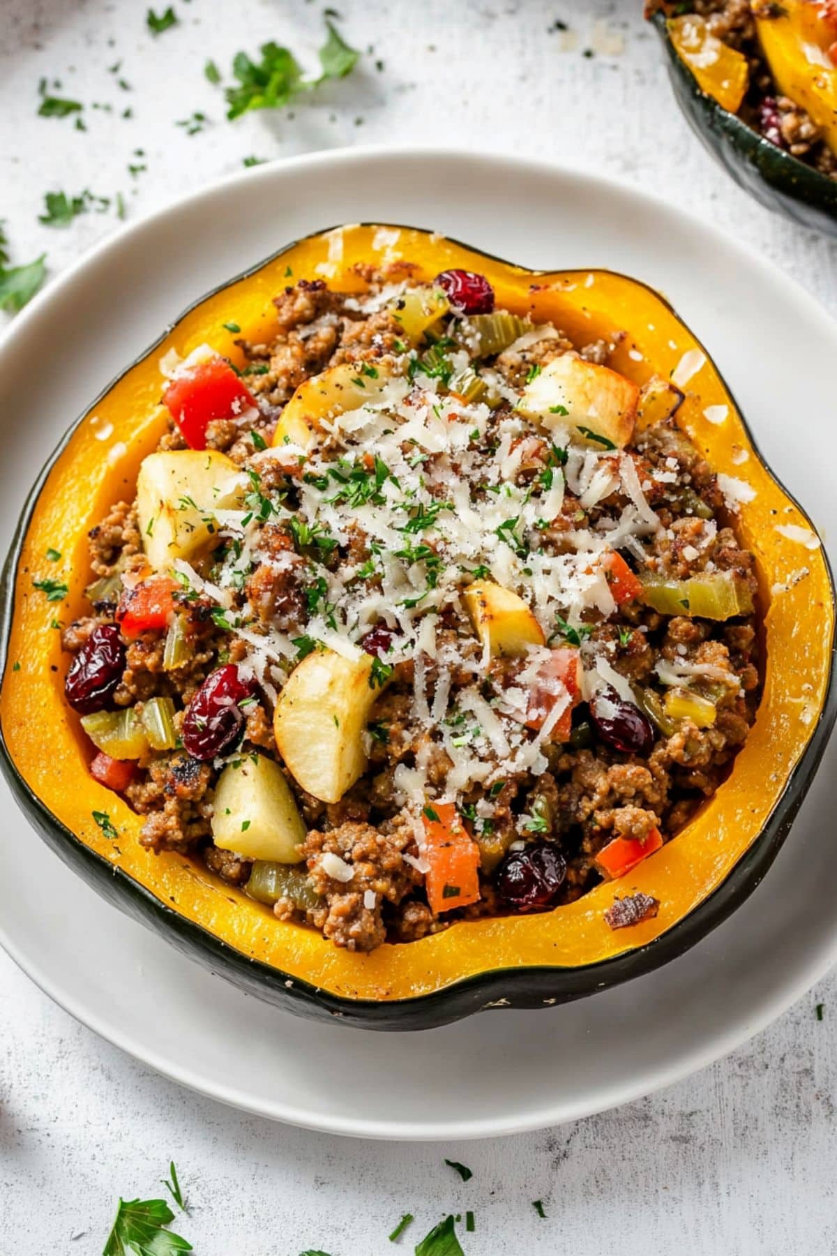 Roasted stuffed acorn with ground beef and veggies filling served in a white plate.