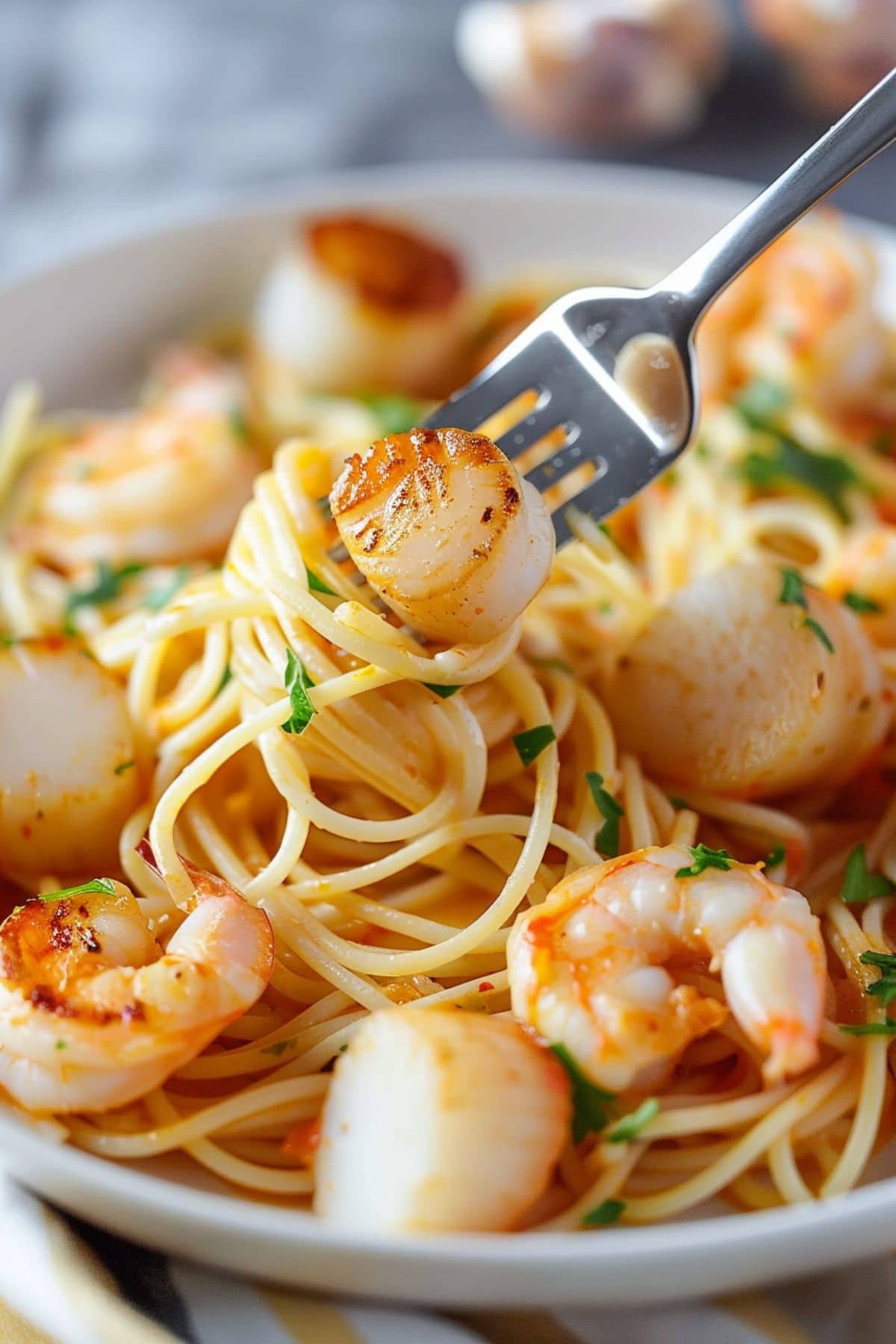 Scallop and shrimp pasta twirled on a fork.