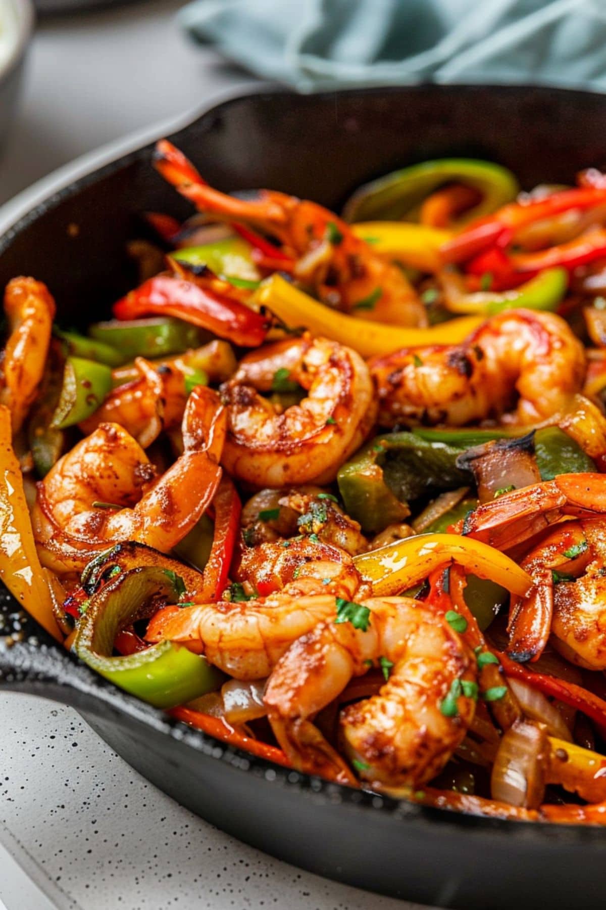 Cast iron skillet pan with shrimp, sliced green, yellow and red bell pepper tossed in spices.