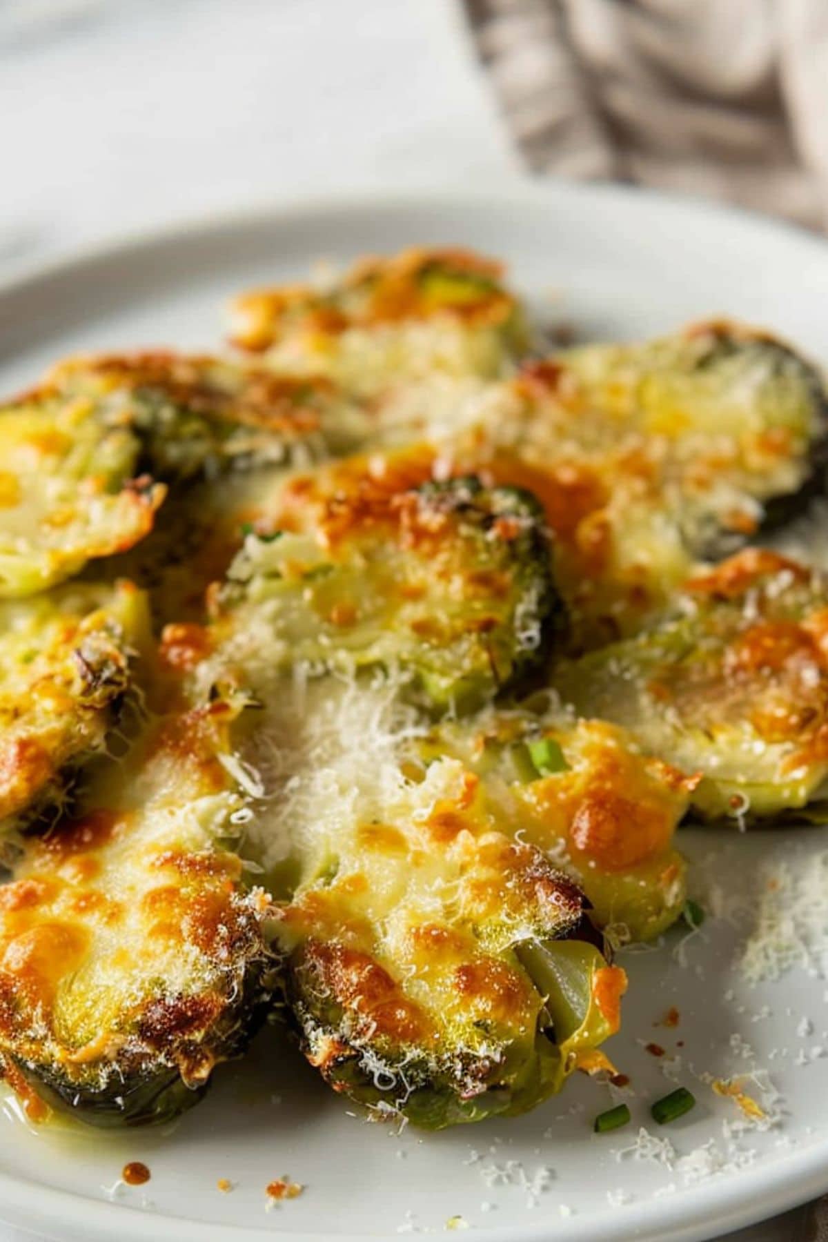 Smashed Brussels sprouts with melted cheese served on a white plate, close up