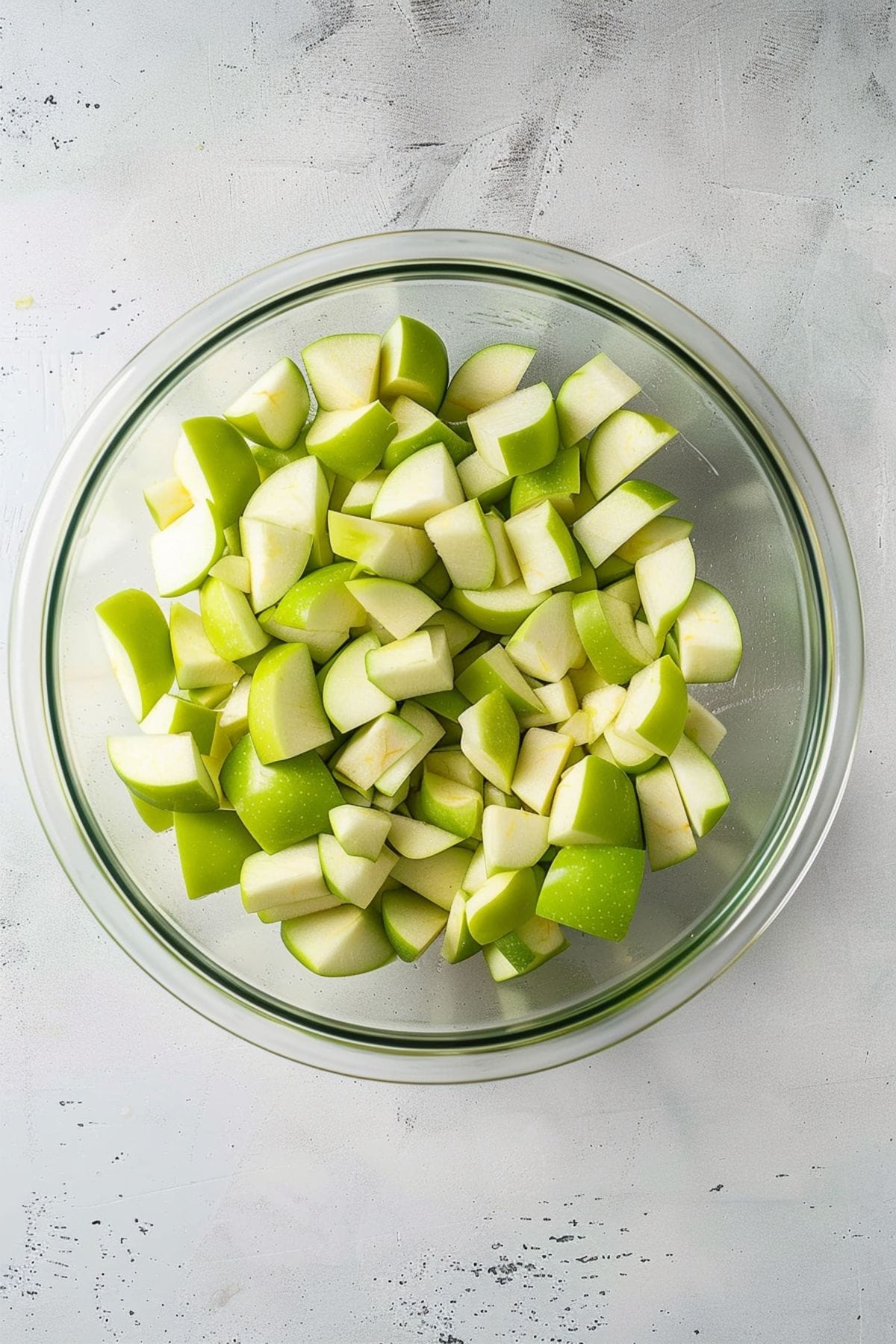 Chopped green apples in a glass mixing bowl.