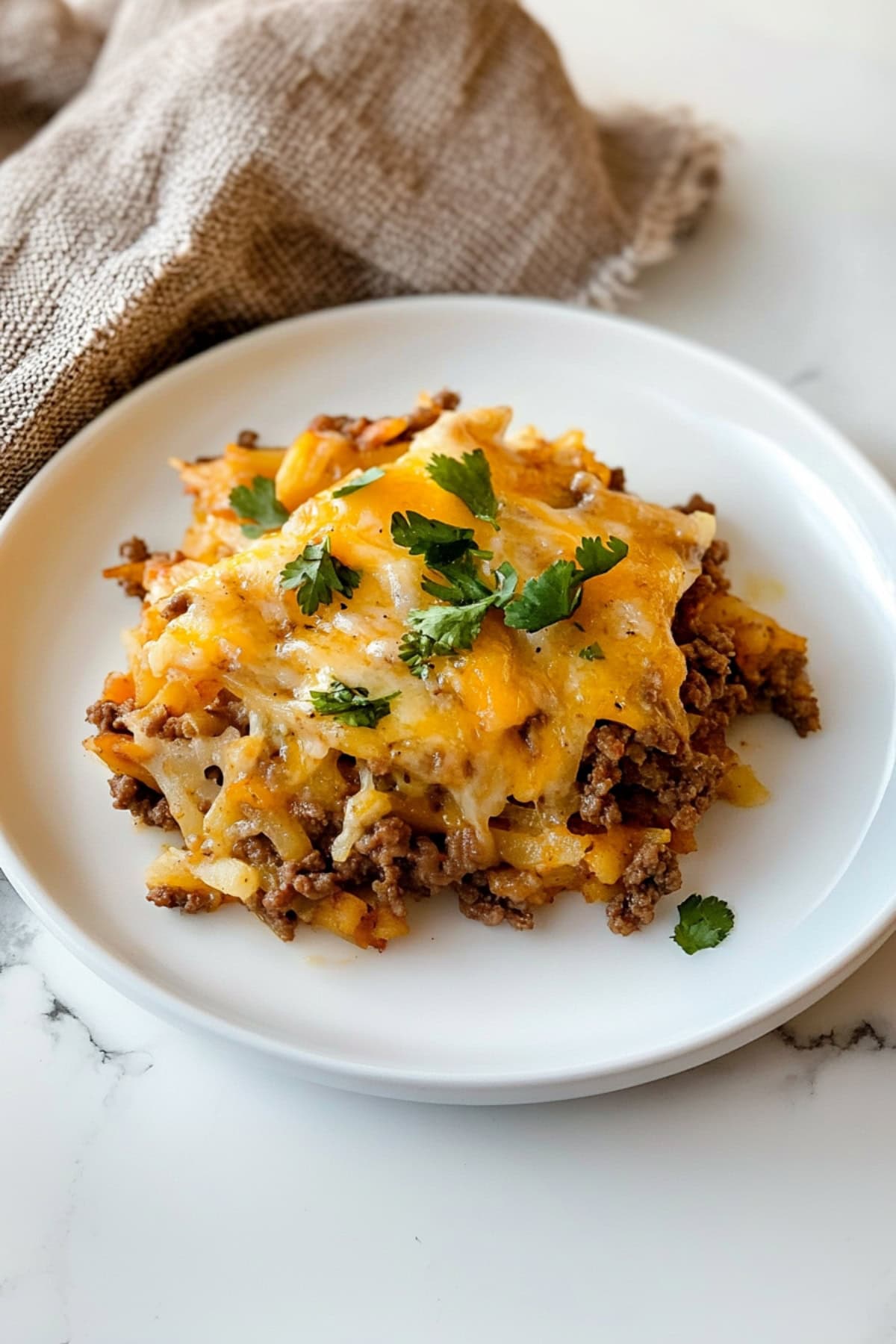 A plate of taco hashbrown casserole with ground beef, garnished with cilantro.