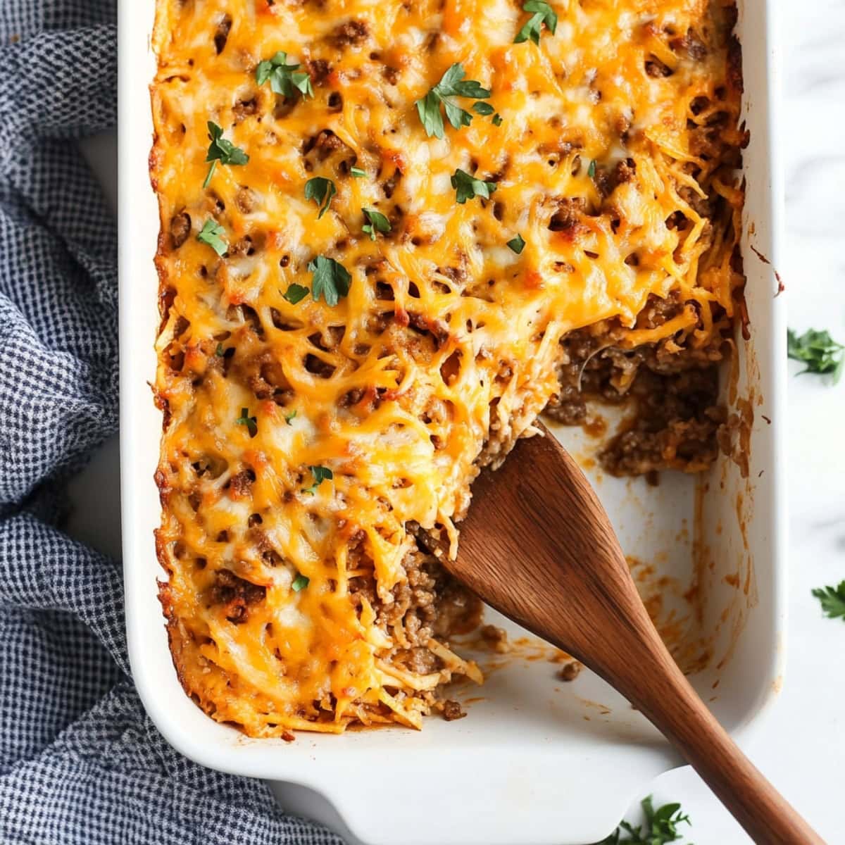 An overhead view of taco hashbrown casserole with ground beef in a baking dish.