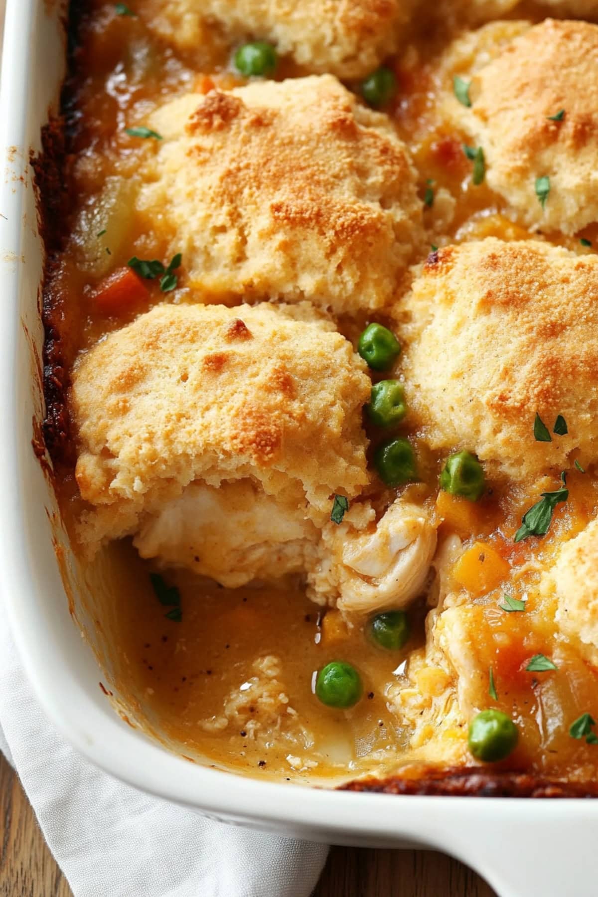 Baked biscuit chicken with creamy sauce and veggies in a baking dish. 