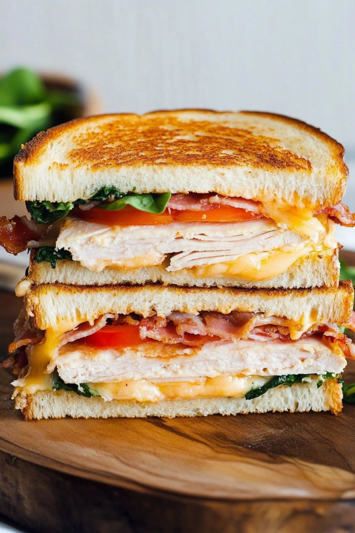 Cheesy turkey grilled cheese sandwich sliced in half served on a wooden board.