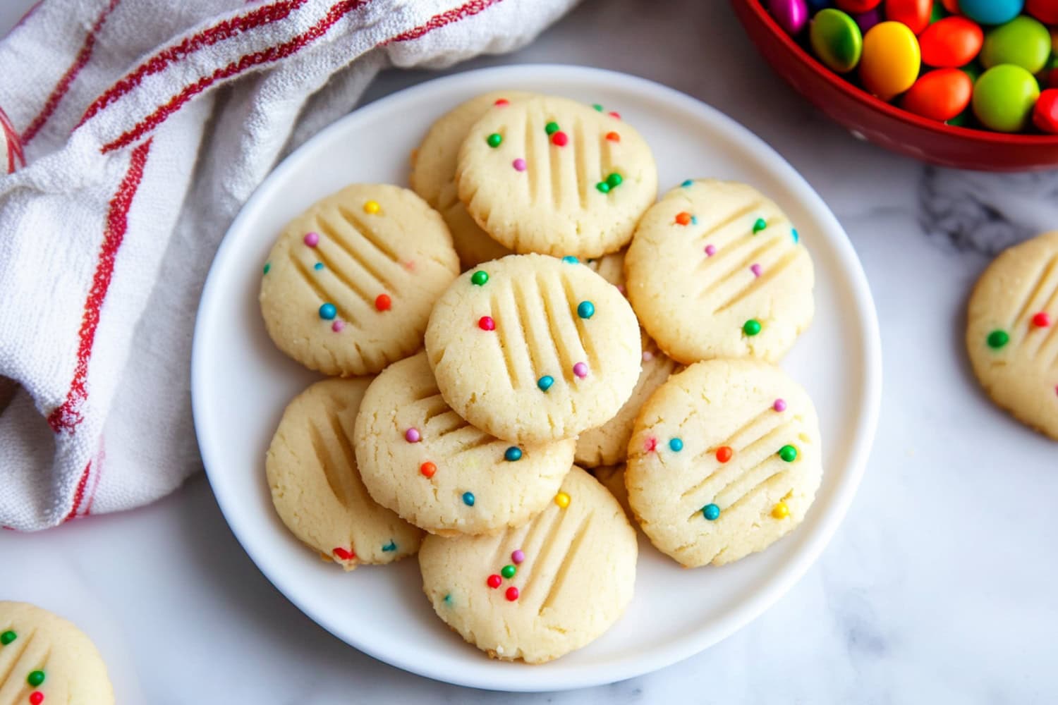 Whipped shortbread cookies with colorful candies in a white plate.