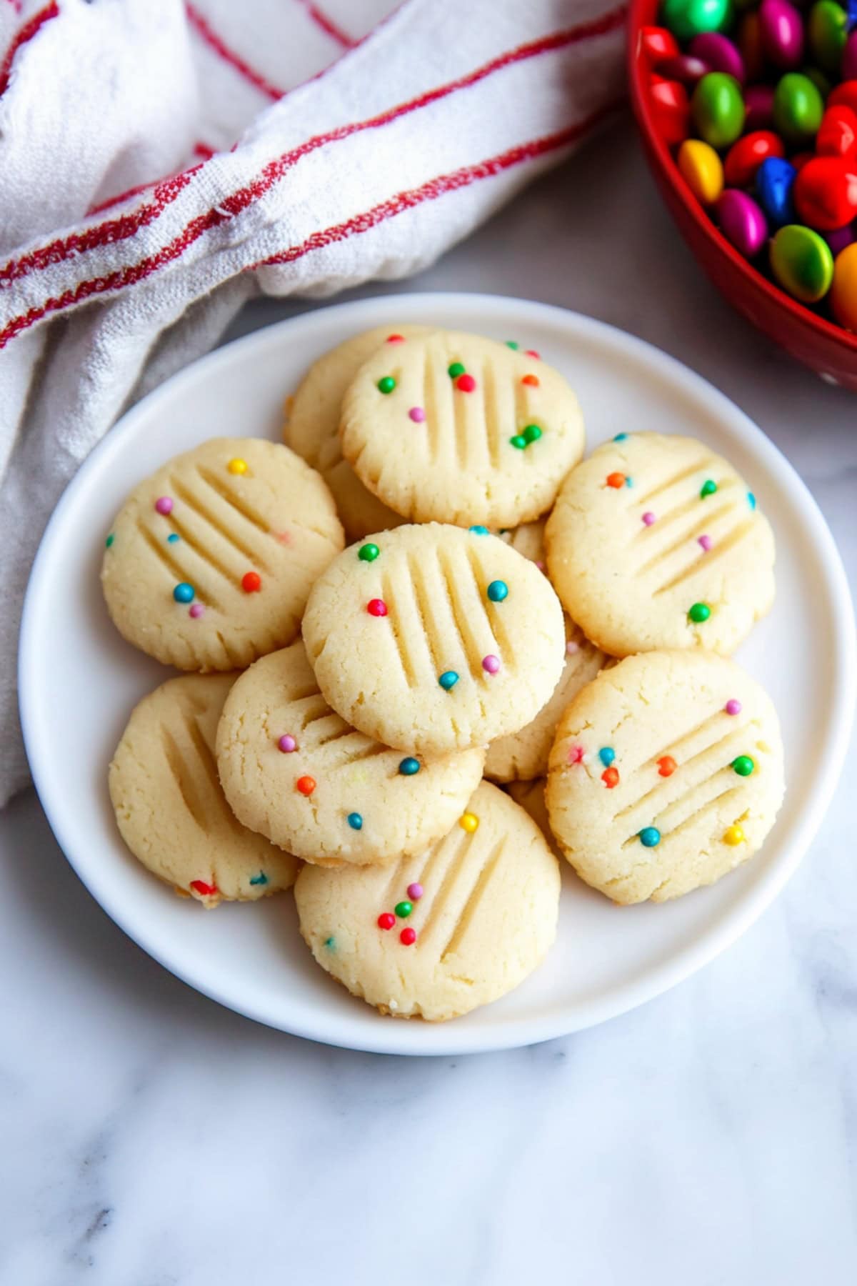 A plate filled with whipped shortbread cookies with decorative candies.