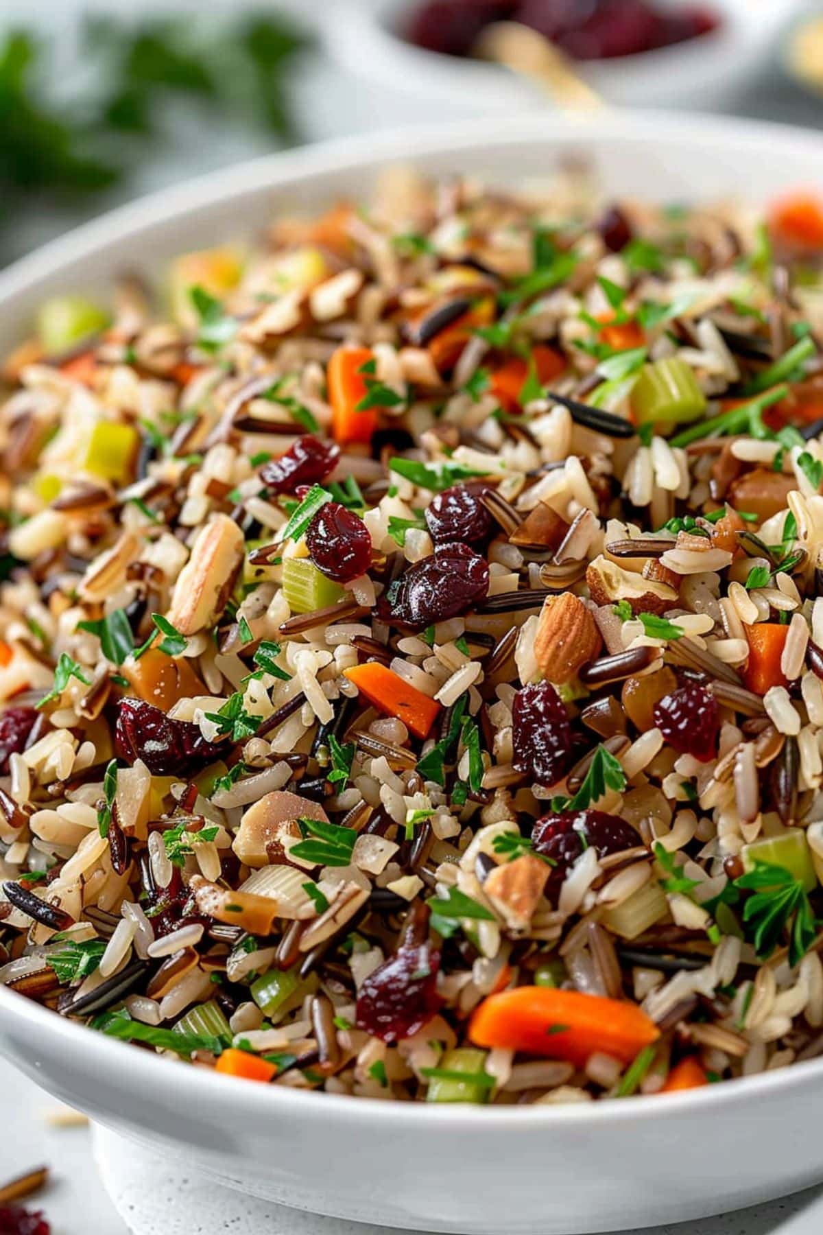 A serving of wild rice pilaf with chopped chopped onion, diced celery, and carrot, slivered almonds and sliced green onions.