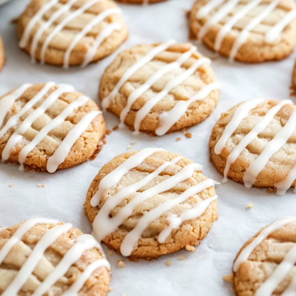 A batch of apple cider cookies with glaze on a parchment paper.