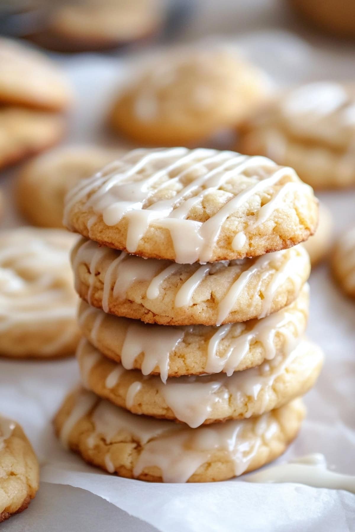 A stack of apple cider cookies with glaze, sitting on a parchment paper.