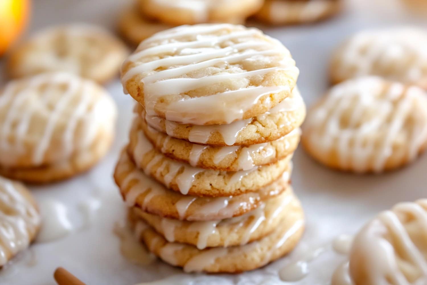 Stacked homemade apple cider cookies with glaze sitting on a parchment paper.