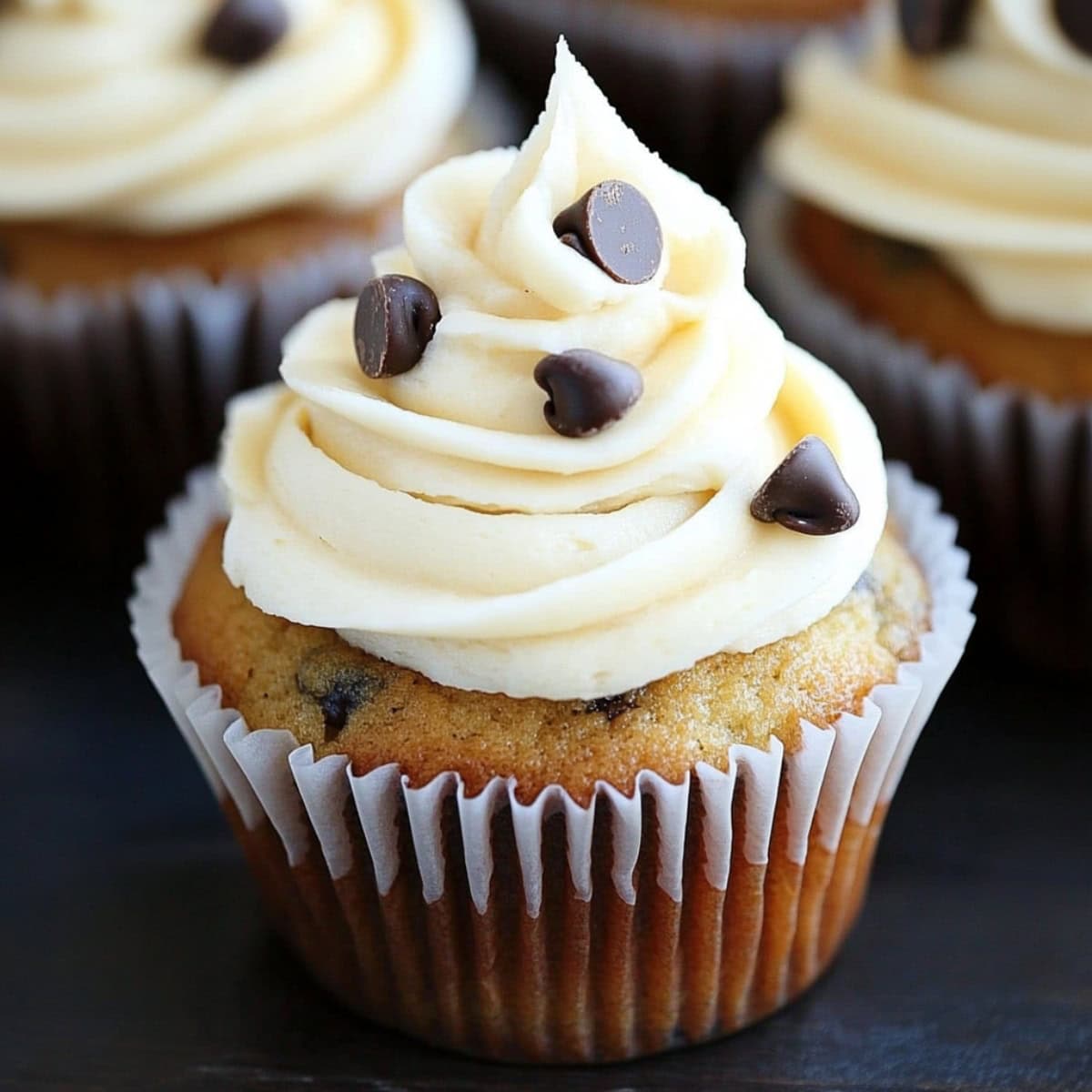 Banana chocolate chip cupcakes topped with a swirl of cream cheese frosting.