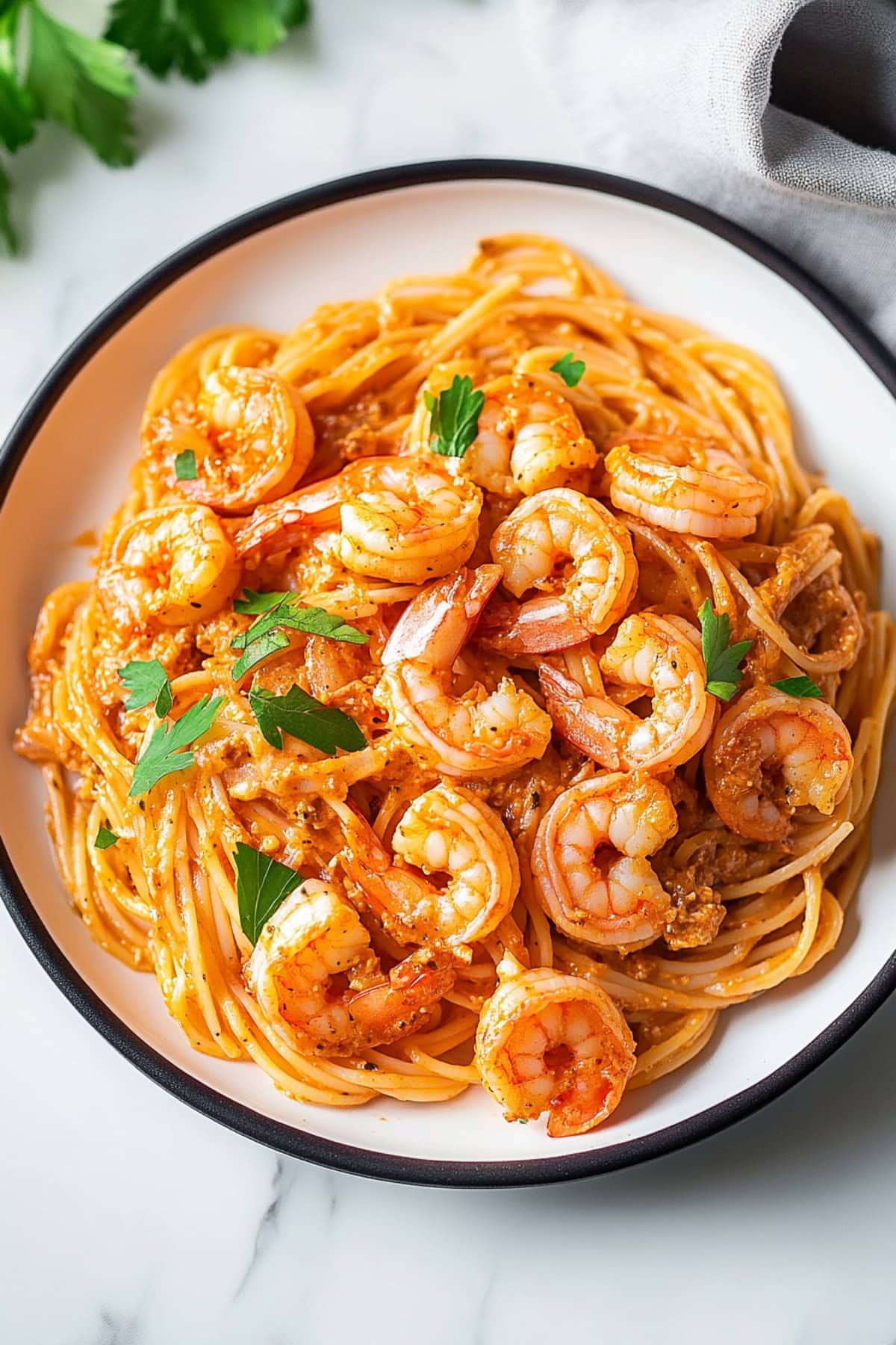 Pasta with shrimp and creamy tomato sauce served in a white plate.