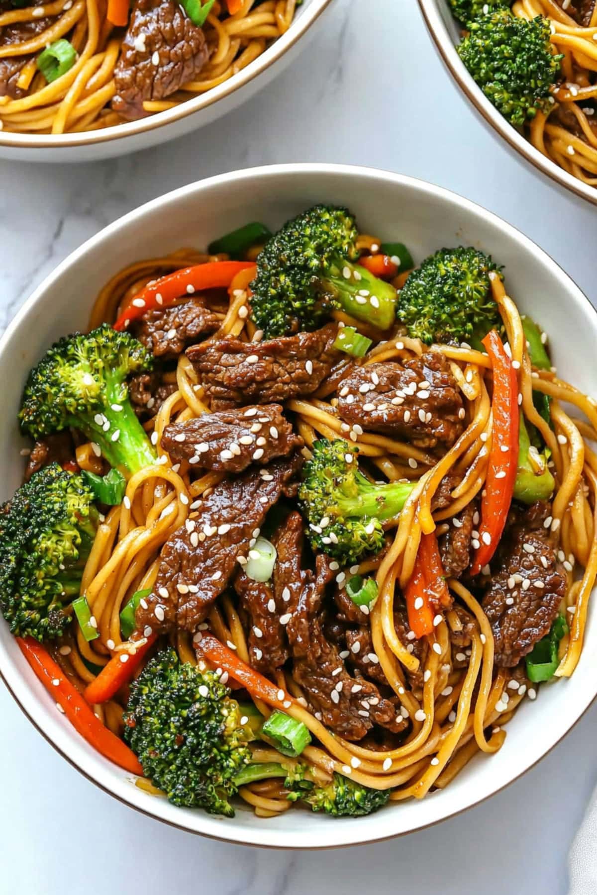 Savory beef and broccoli lo mein with carrots and green onions.