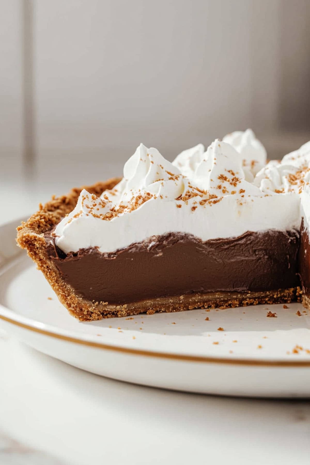 Slice portion missing chocolate pudding pie topped with whipped cream served in a white plate.