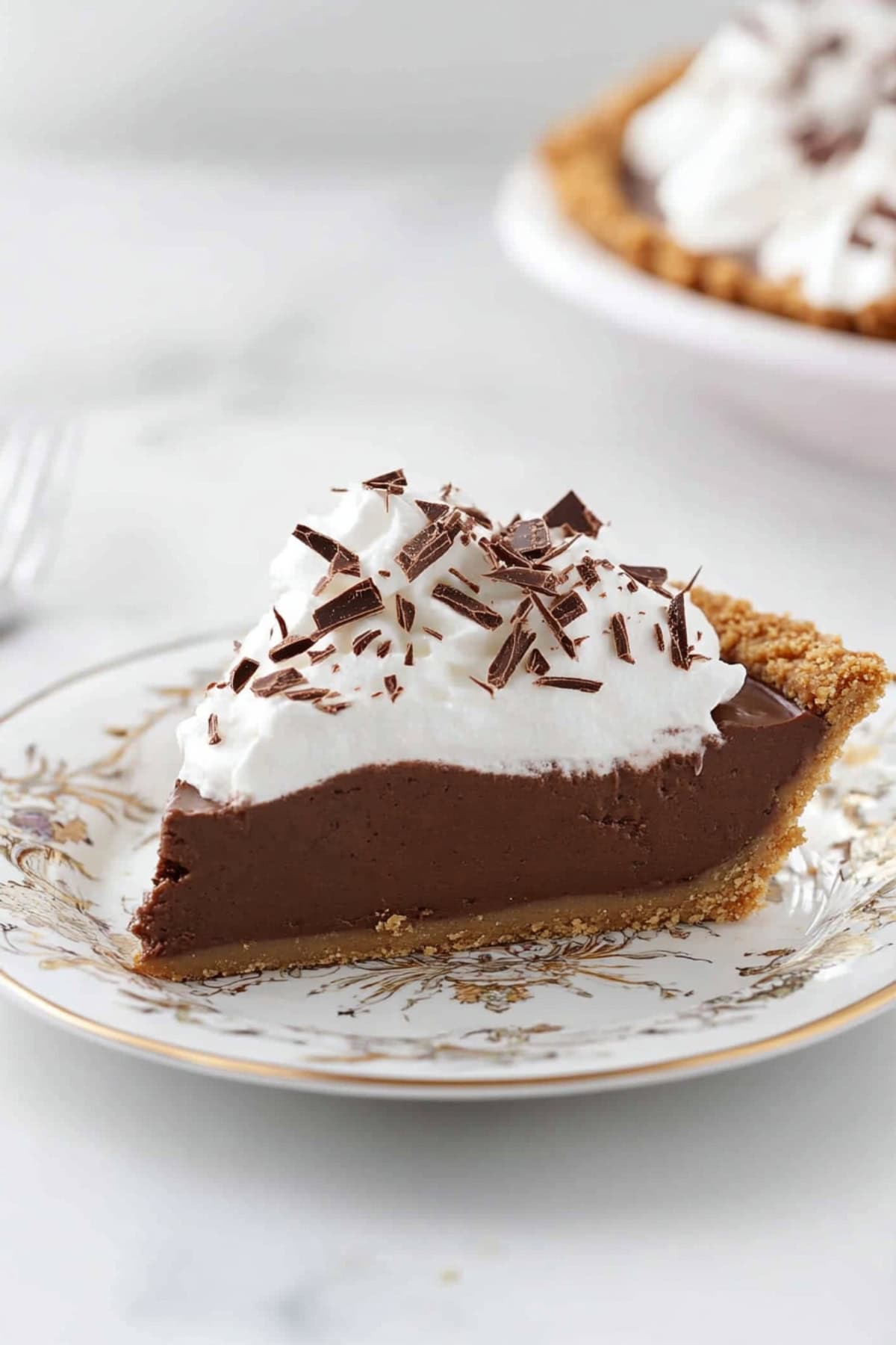 A slice of chocolate pudding pie with whipped cream layer on top garnished with chocolate shavings.