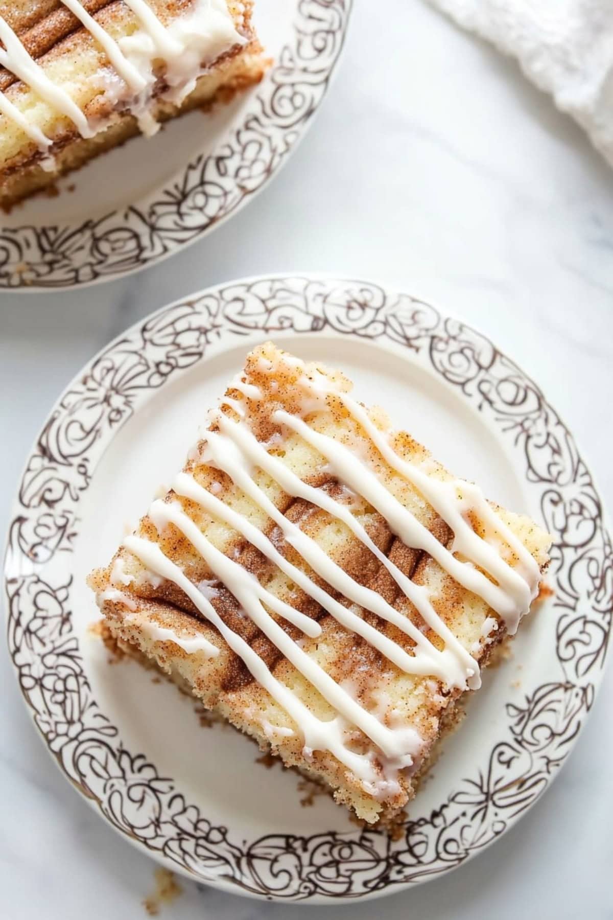 Square slice of cinnamon roll cake drizzled with white glaze on top served in a plate..