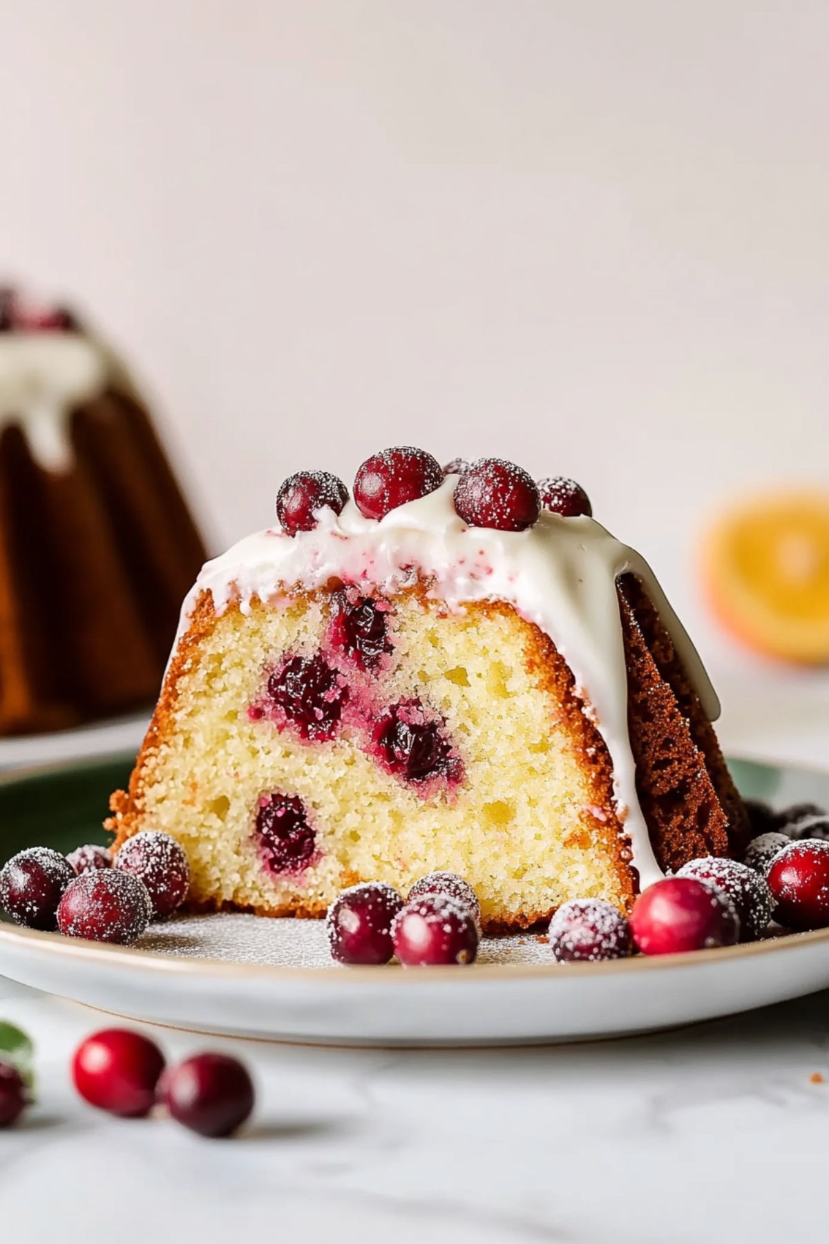 Sliced cranberry orange bundt cake with frosting in a plate.