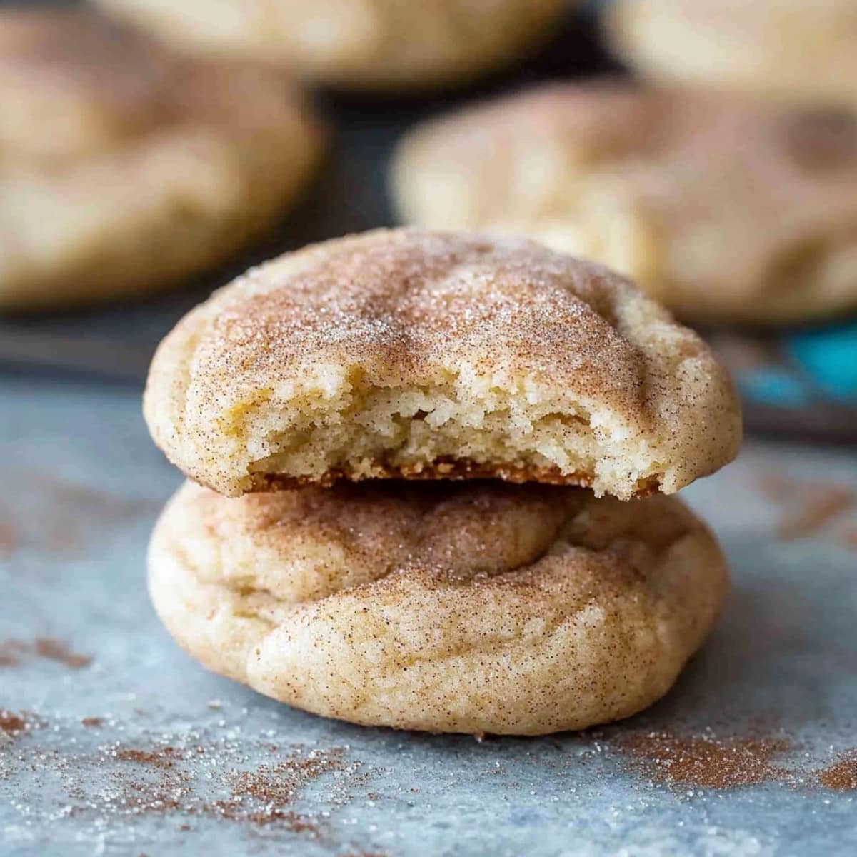 Bitten cream cheese snickerdoodle with the bunch of other cookies sitting on a rustic table.