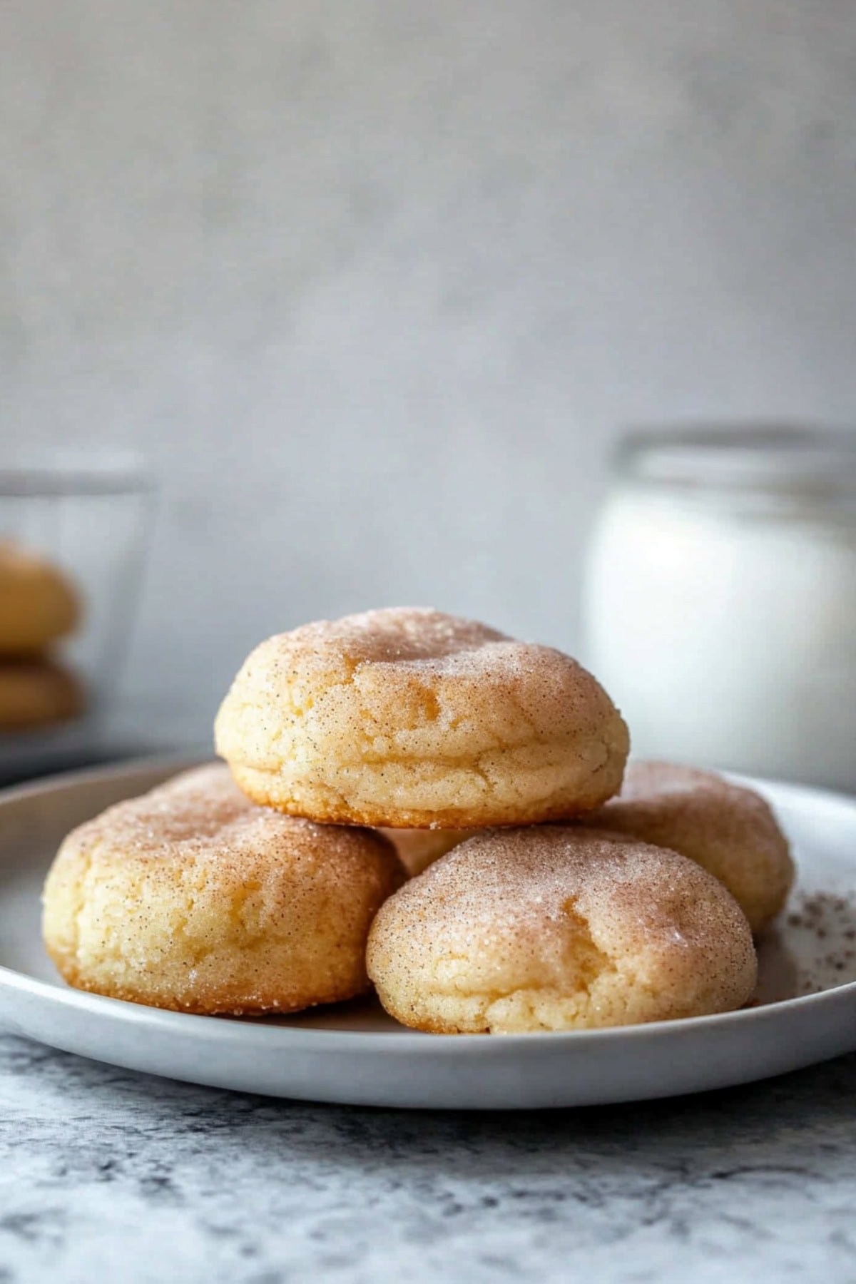 Bunch of cheese snickerdoodles served in a plate with a glass of milk on the side.