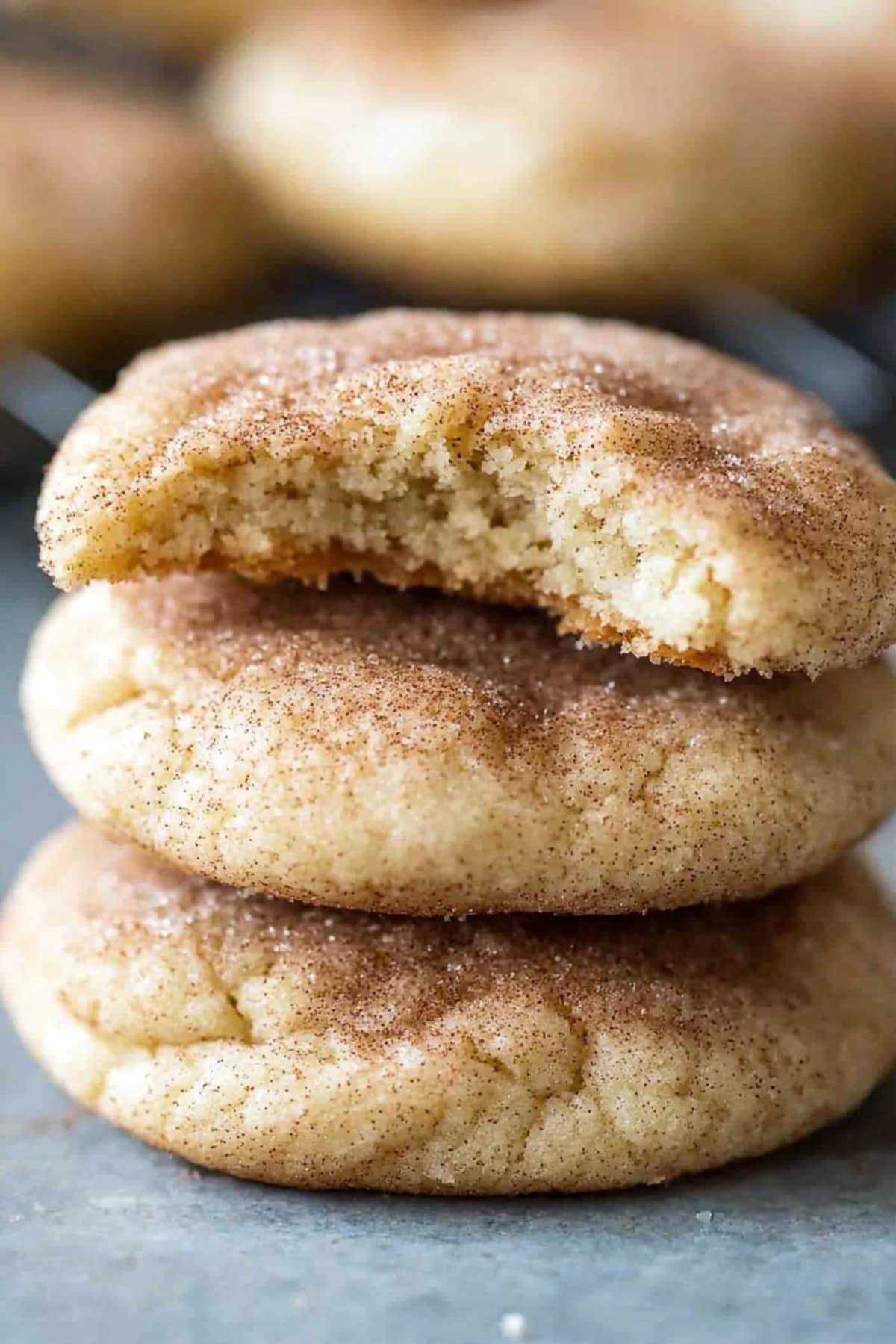 Bitten piece of cream cheese snickerdoodle sitting on top of other cookies. 