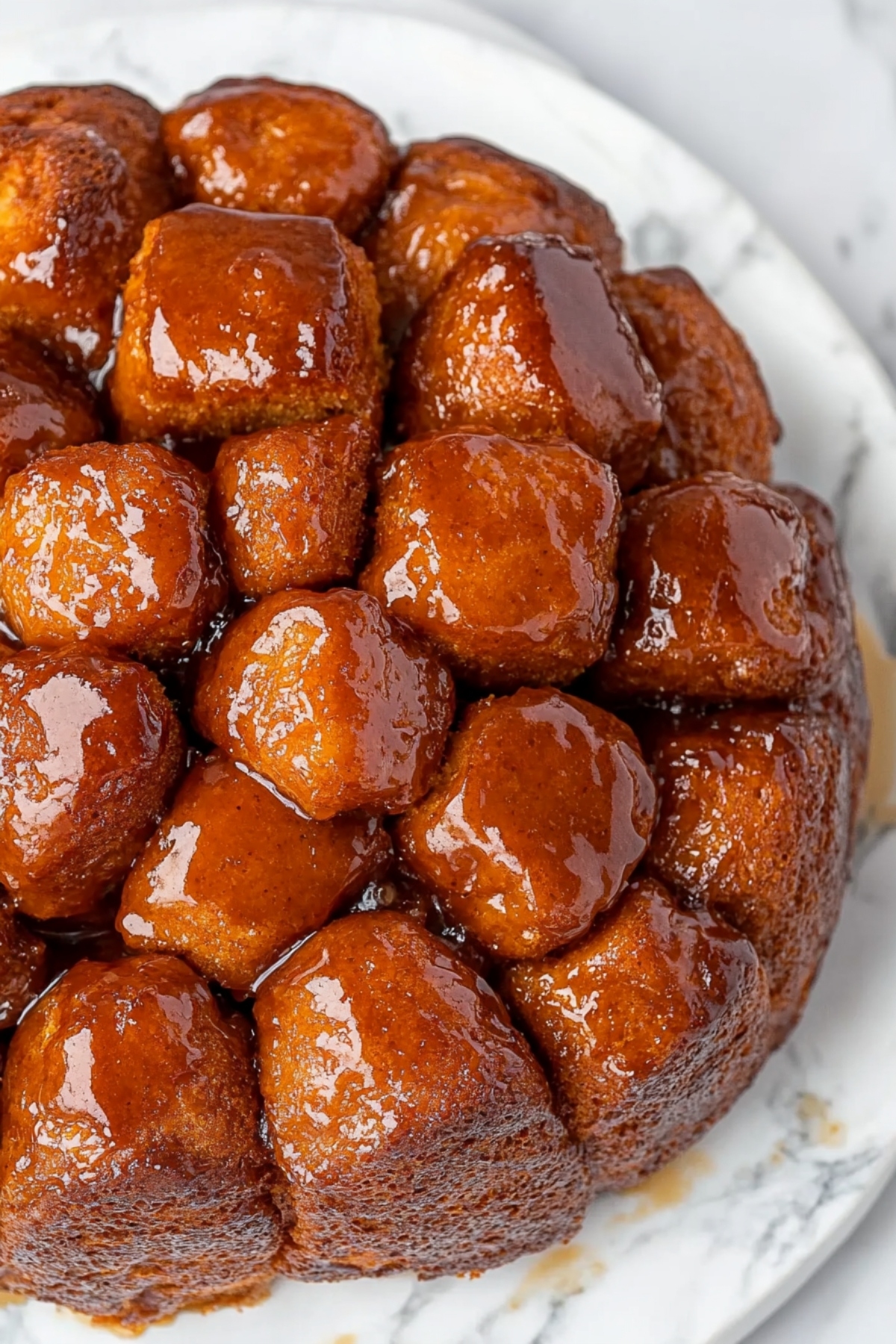 Crockpot monkey bread topped with brown sugar syrup on a white plate.