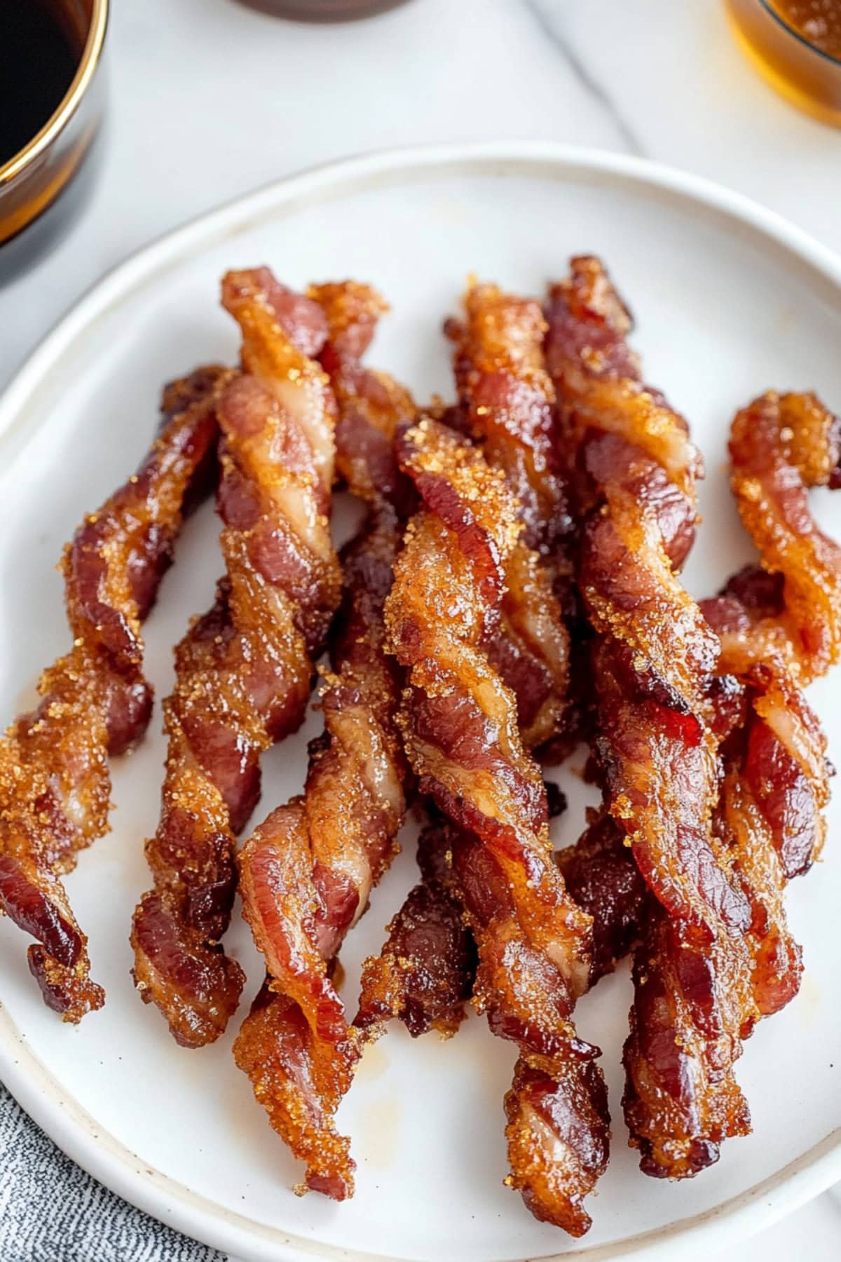 Golden, crunchy bacon twists arranged on a plate, showcasing their crispy texture and twisted shape.