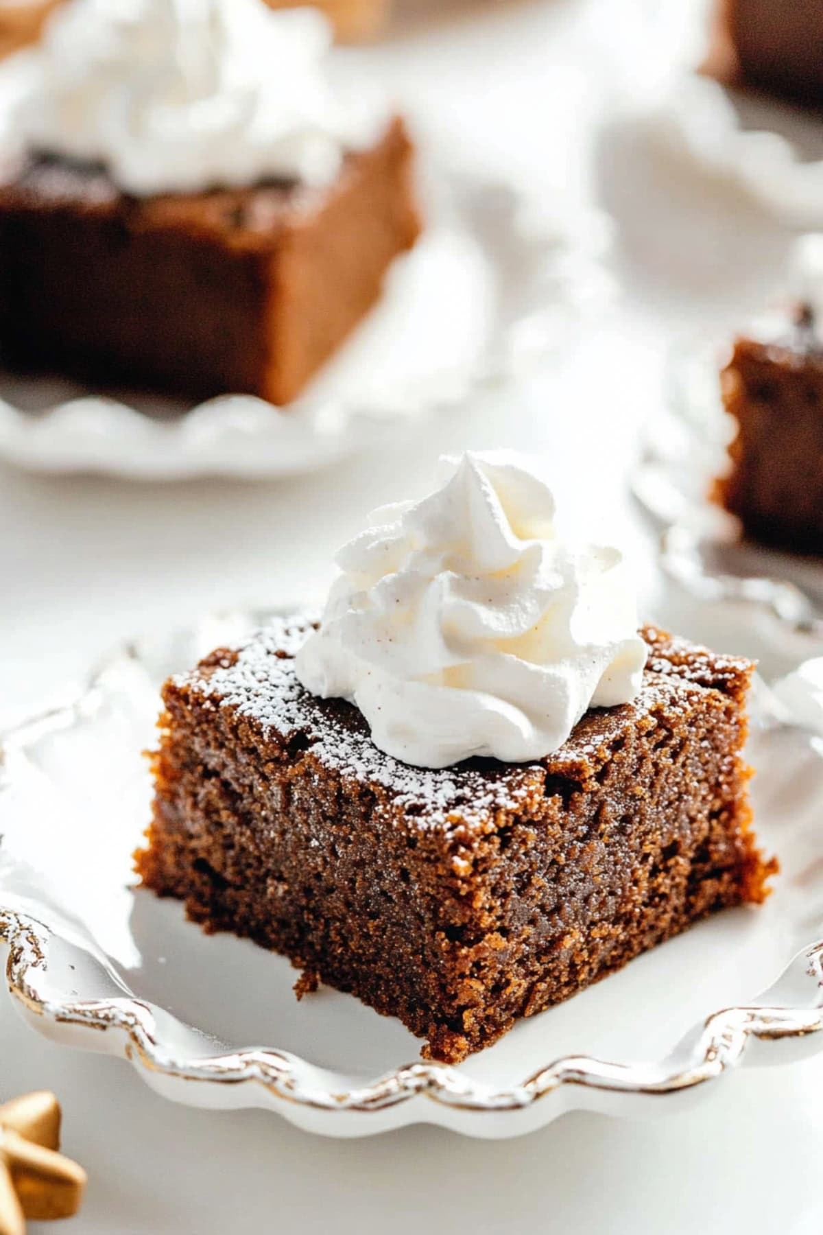 A piece of gingerbread cake with powdered sugar and whipped cream in a plate.