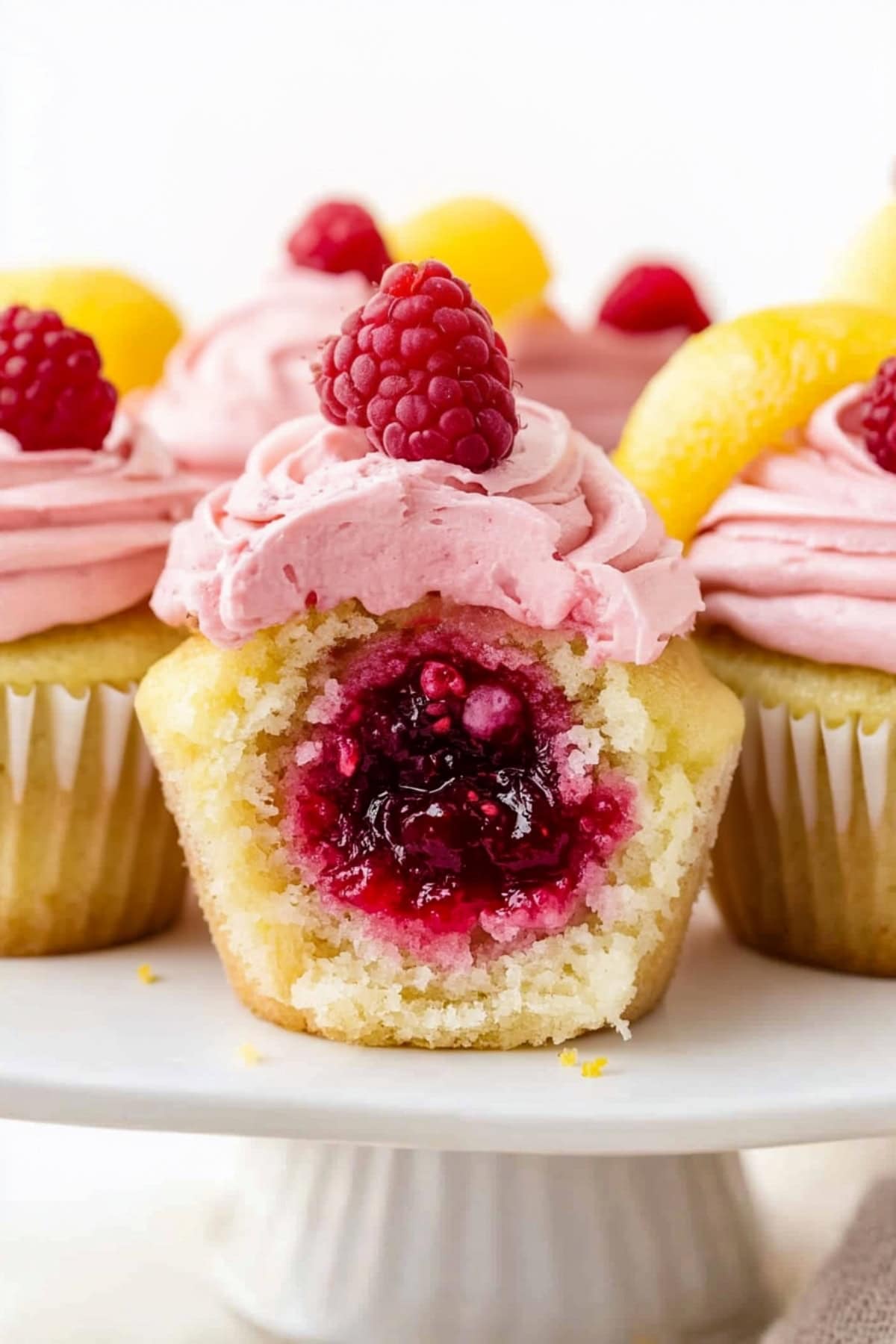 Lemon raspberry cupcake cut in half showing the raspberry filling sitting on a cake tray.