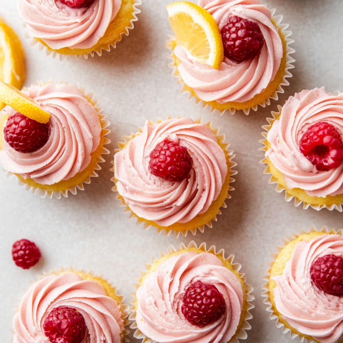 Top view of lemon cupcake with raspberry frosting and garnish decorated with lemon wheel.