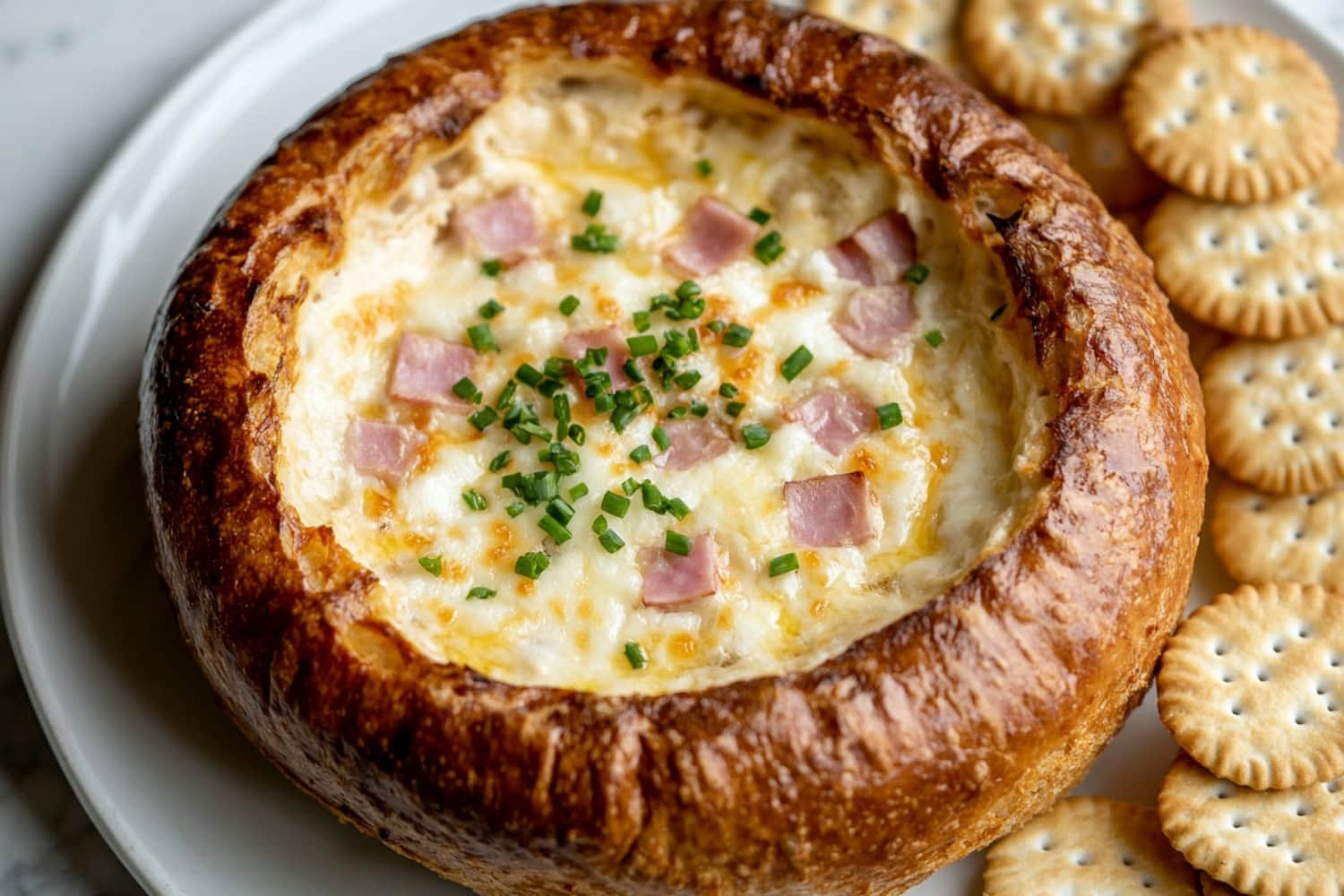 Mississippi sin dip served in a hollow loaf bread with a platter of crackers.