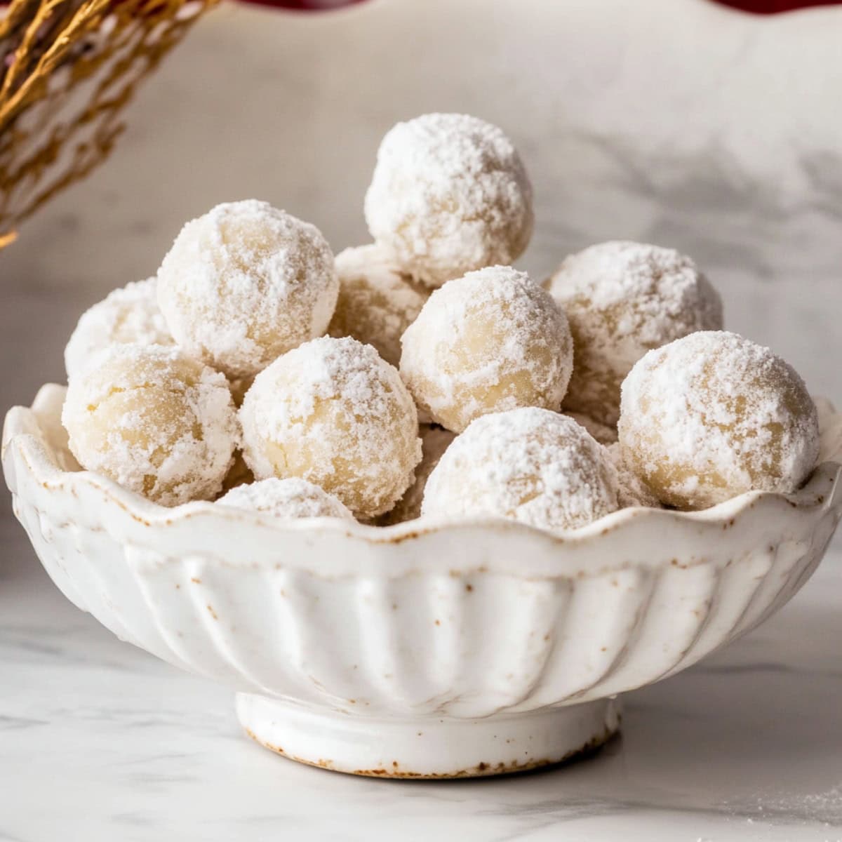 Bunch of pecan snowball cookies arranged in a white  bowl.