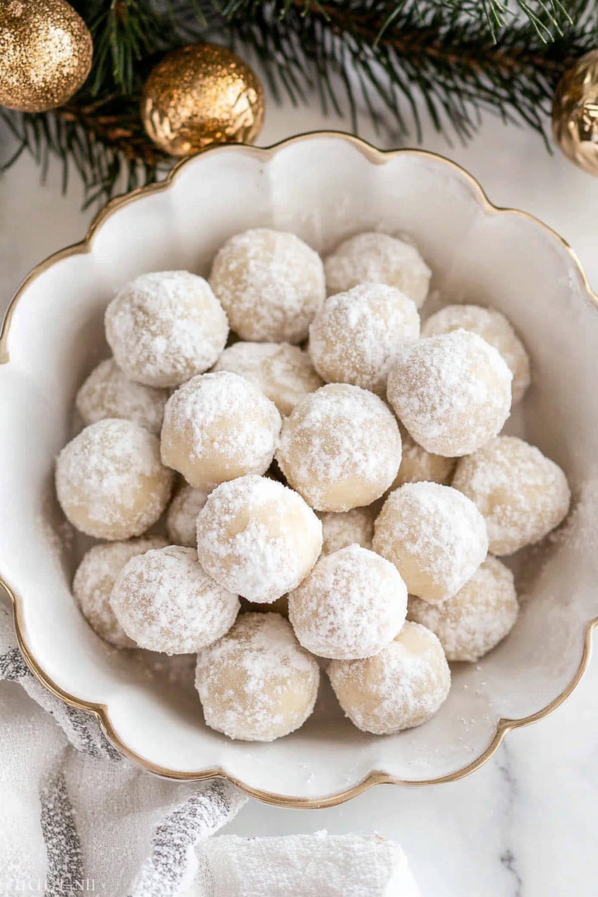 Top view of pecan snowball cookies in a white bowl.