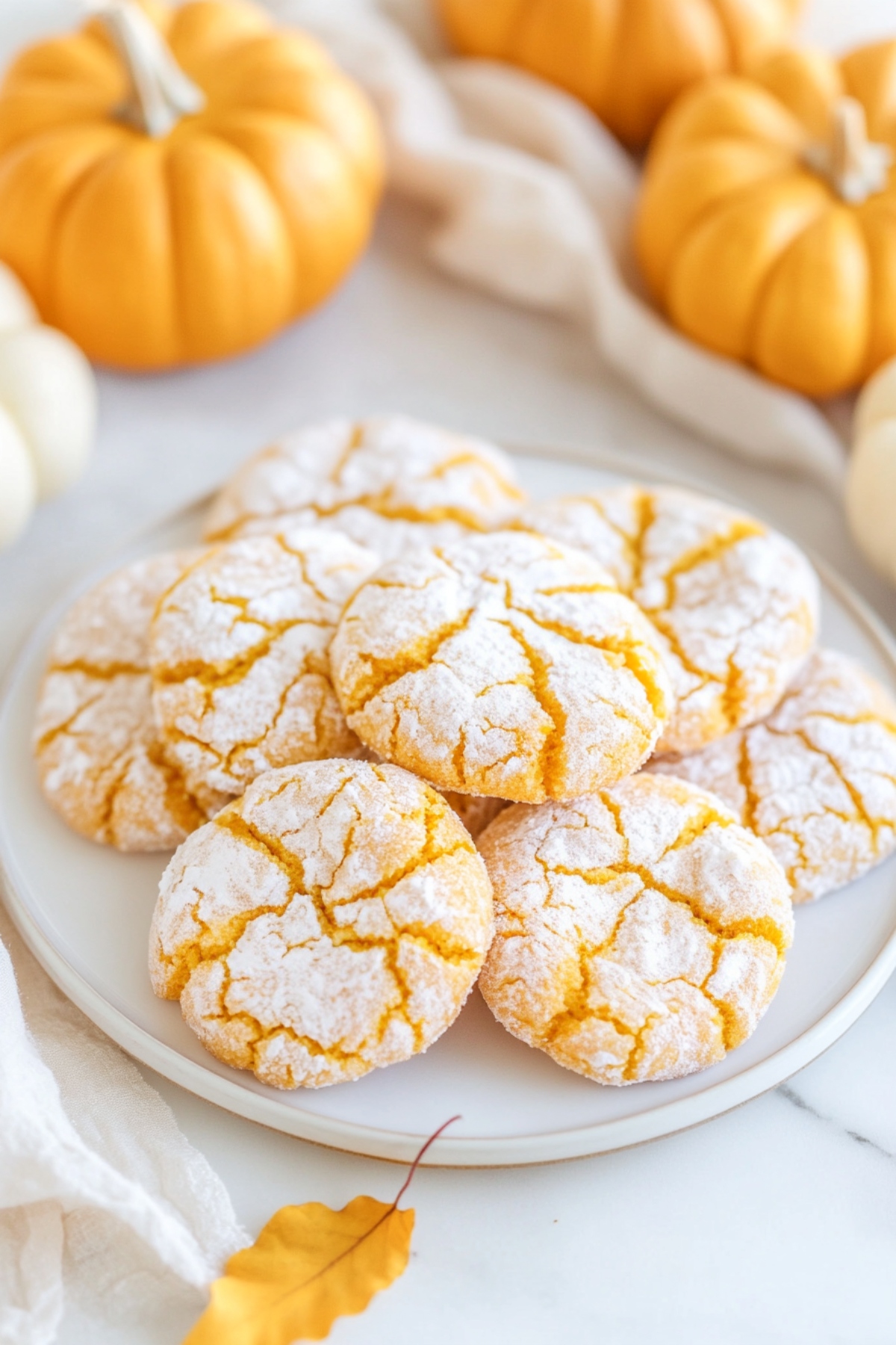 Bunch of pumpkin crinkle cookies coated with powdered sugar served in a white plate.