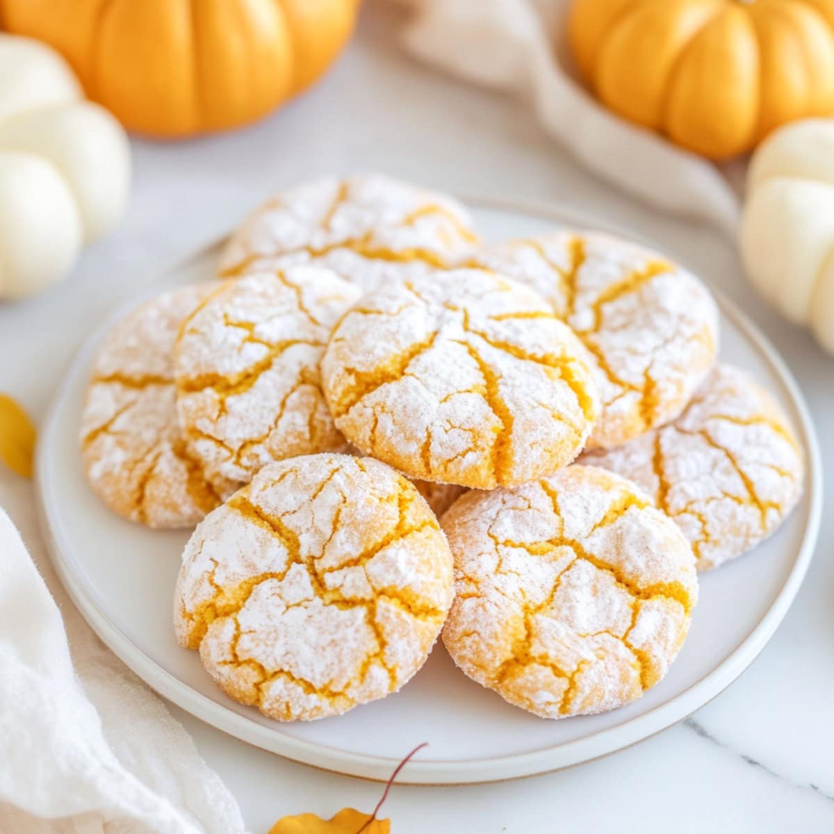 A platter of powdered sugar coated pumpkin crinkle cookies.