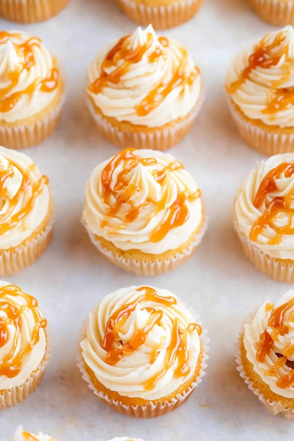 Cupcakes with vanilla frosting drizzled with salted caramel sauce, top view.