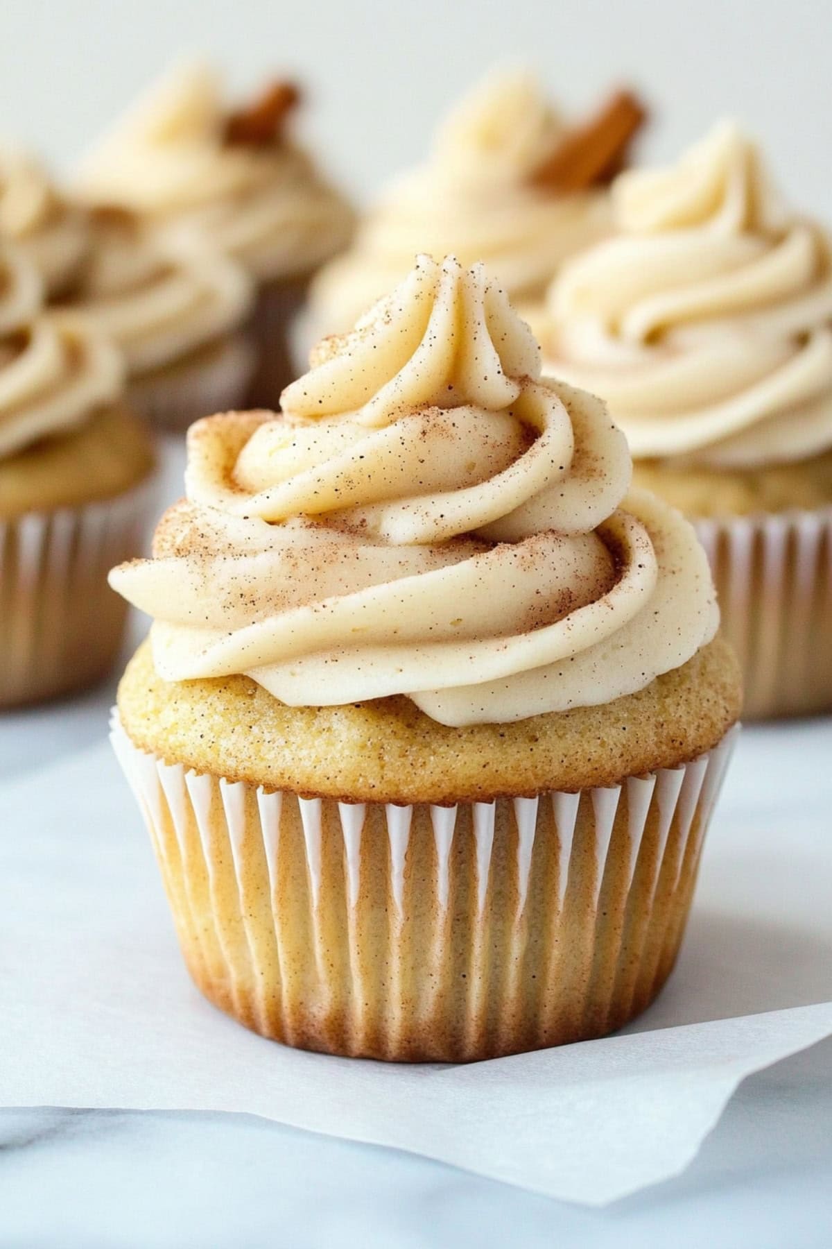 Cinnamon cupcakes topped with creamy frosting dusted with ground cinnamon.