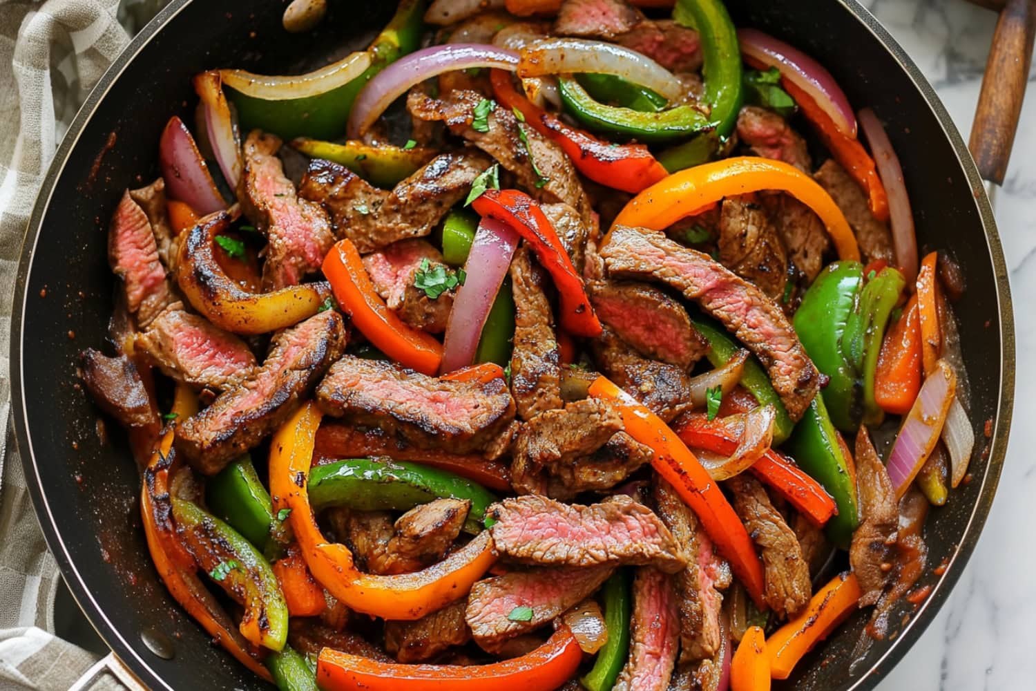 Tender steak fajita slices with colorful bell peppers in a skillet.